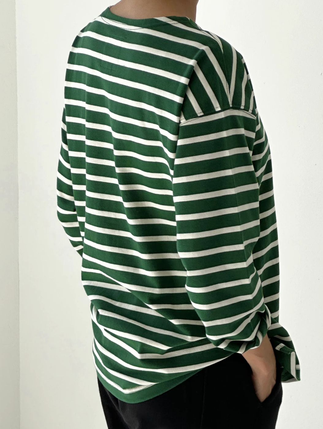 Green and white striped long-sleeve shirt worn by a person on a plain background