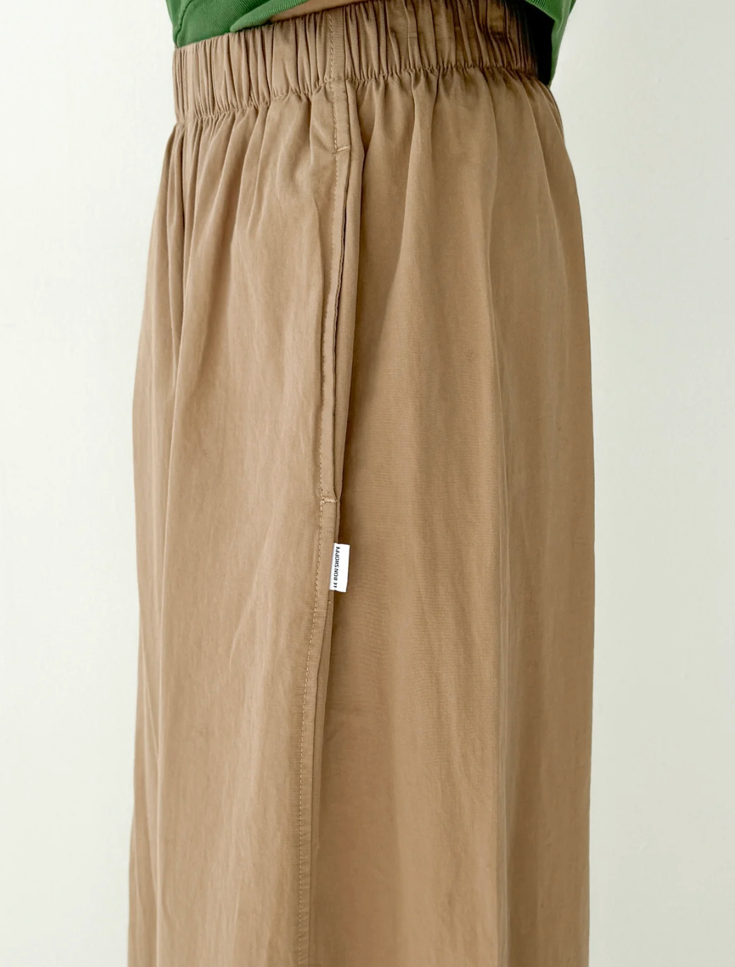 Beige pants with a visible brand label on a white background