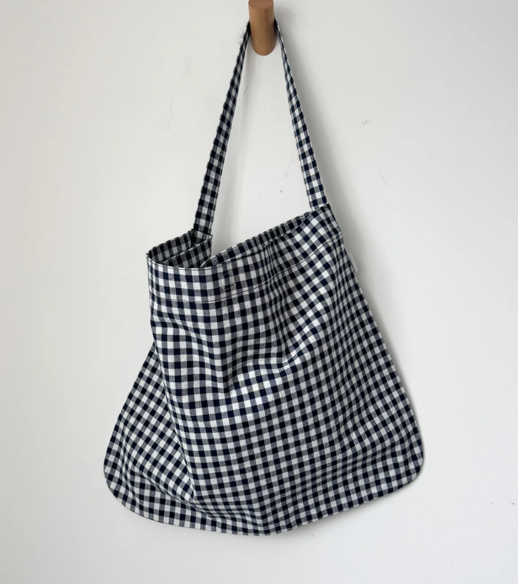 Black and white checkered bag hanging on a wooden hook against a white background