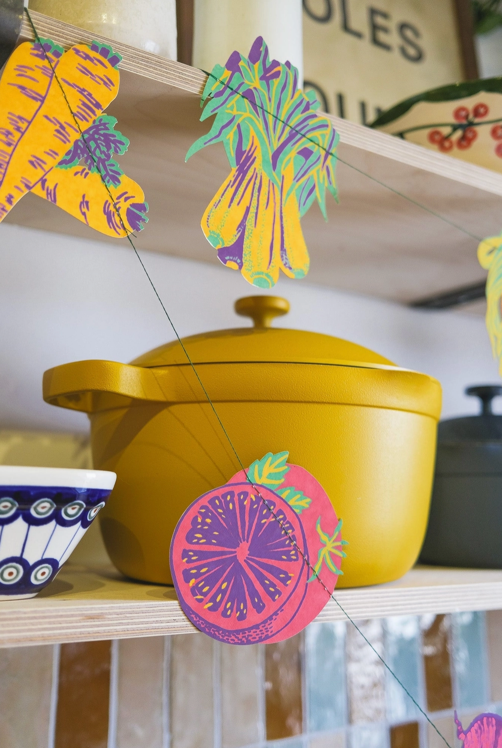 Yellow pot with colorful veggie designs on a shelf