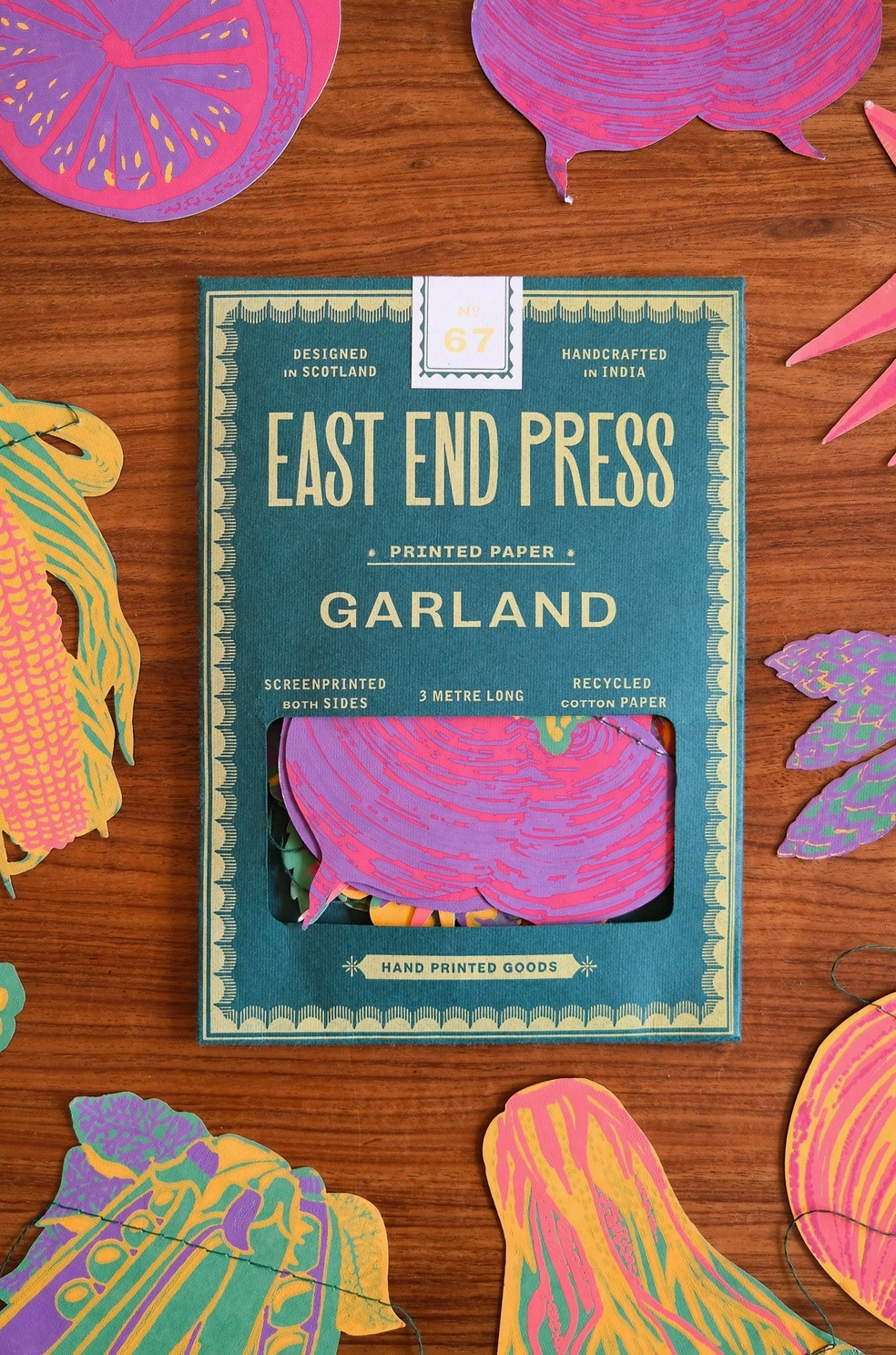 East End Press Garland printed paper package on a wooden surface with colorful paper cutouts.