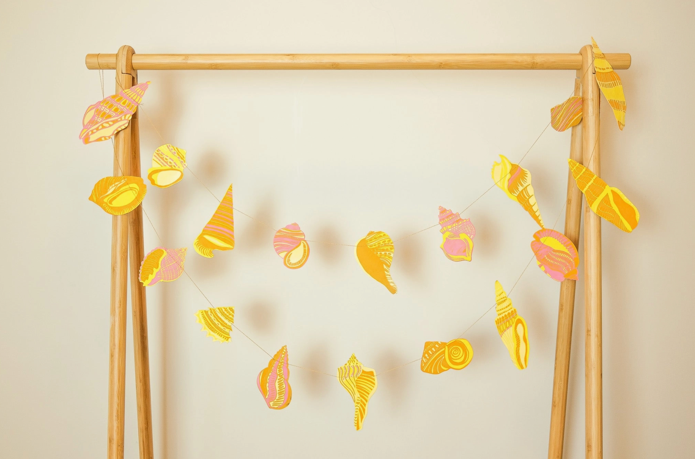 Decorative wall hanging with colorful shell ornaments on a wooden frame against a beige background.