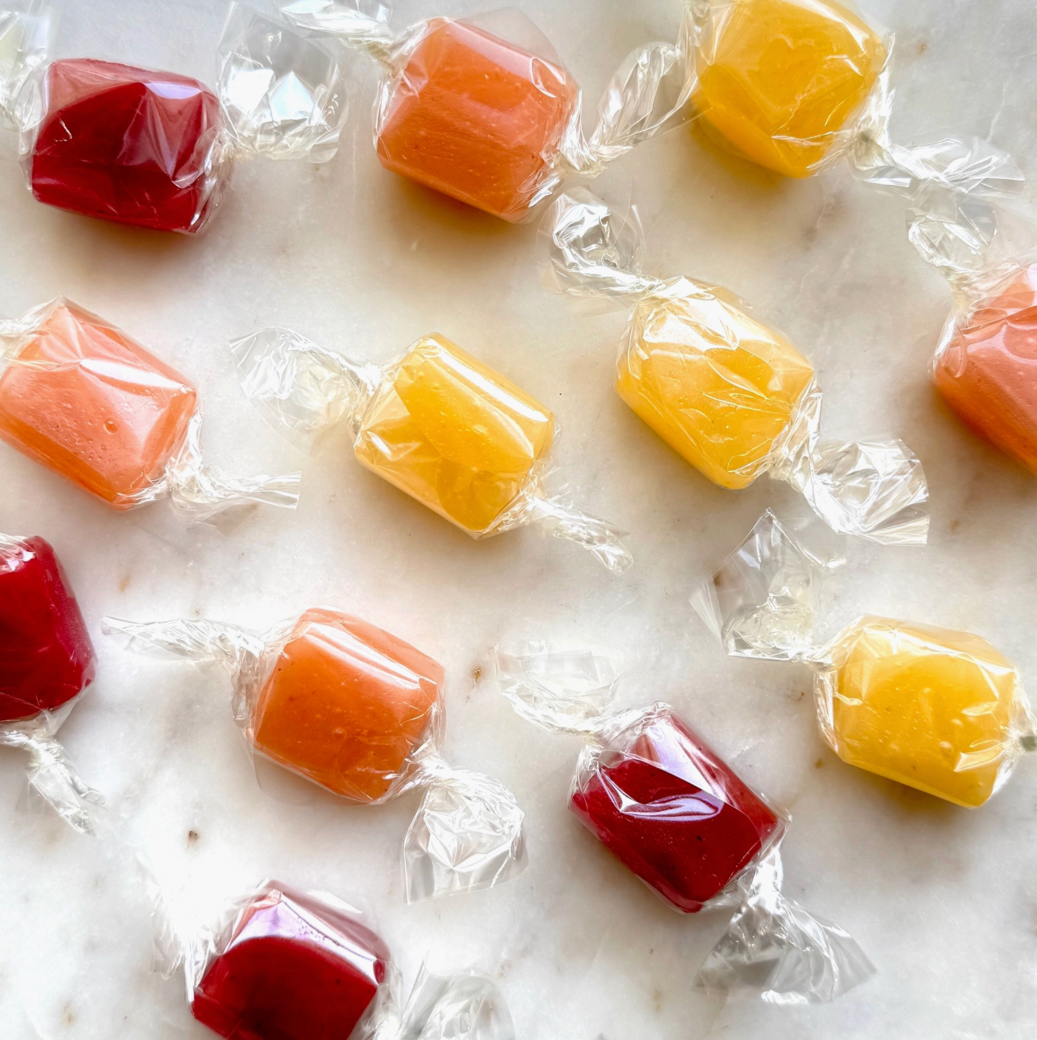 Colorful caramels in clear wrappers on a marble surface