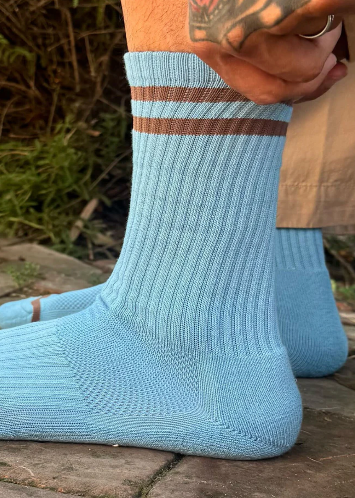 Light blue socks with a brown stripe worn by a person outdoors.