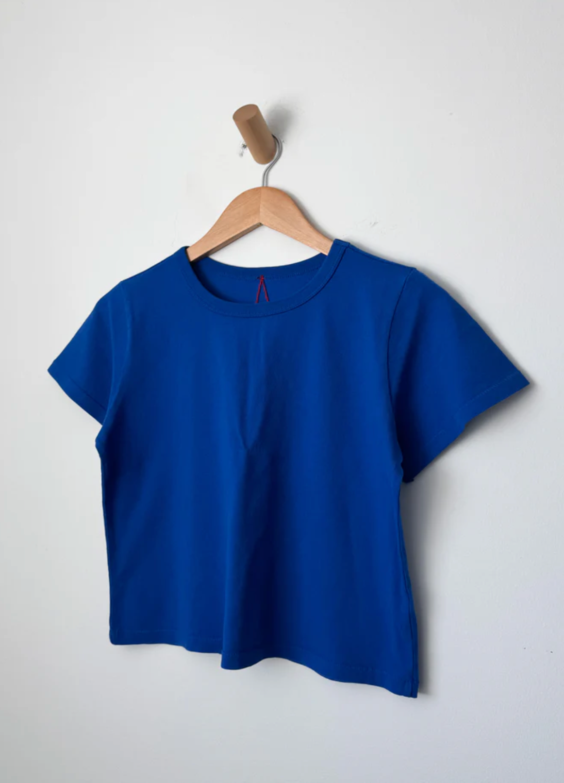 Blue t-shirt on a wooden hanger against a white background