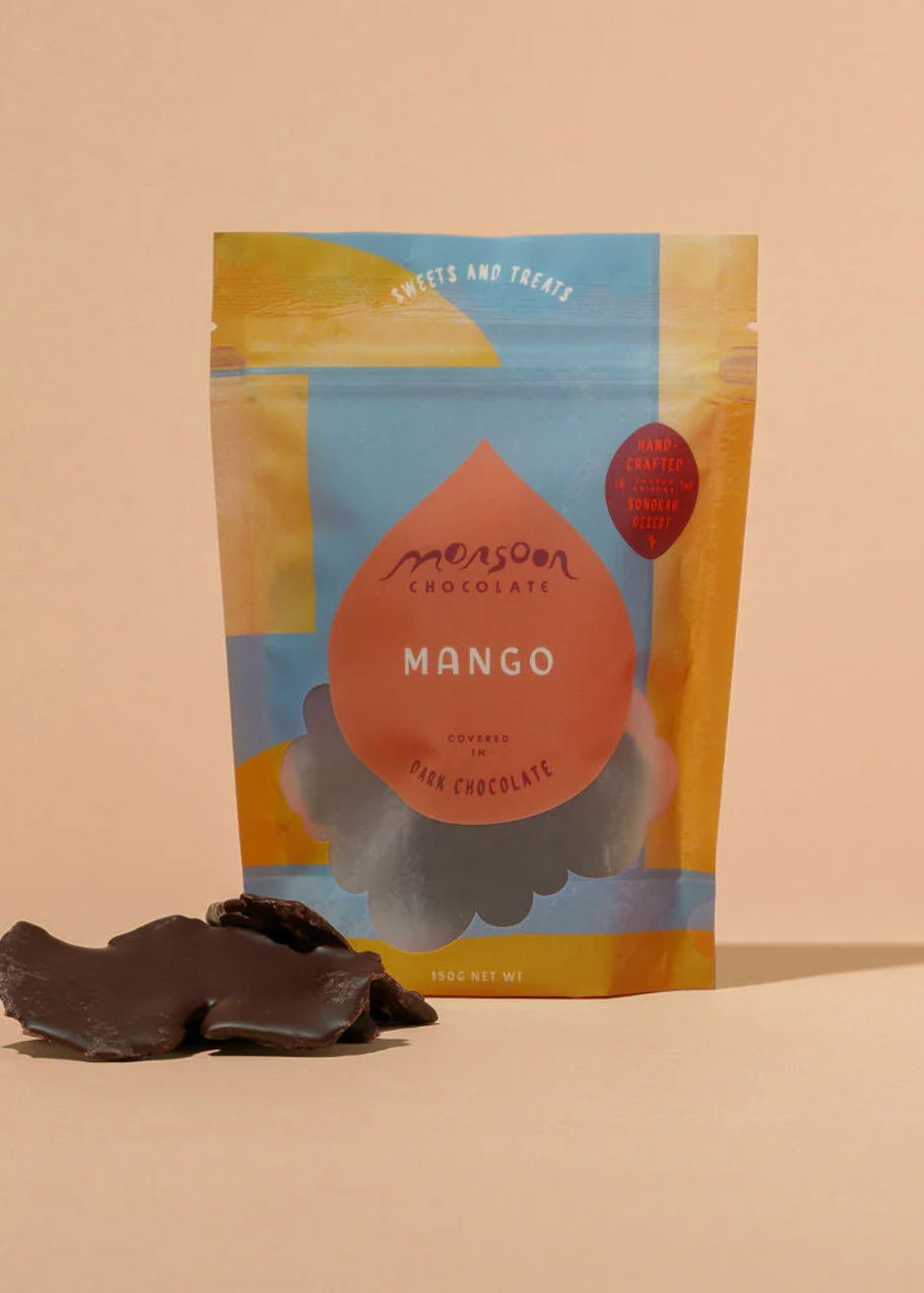 Mango covered in chocolate with a colorful packaging on a beige background