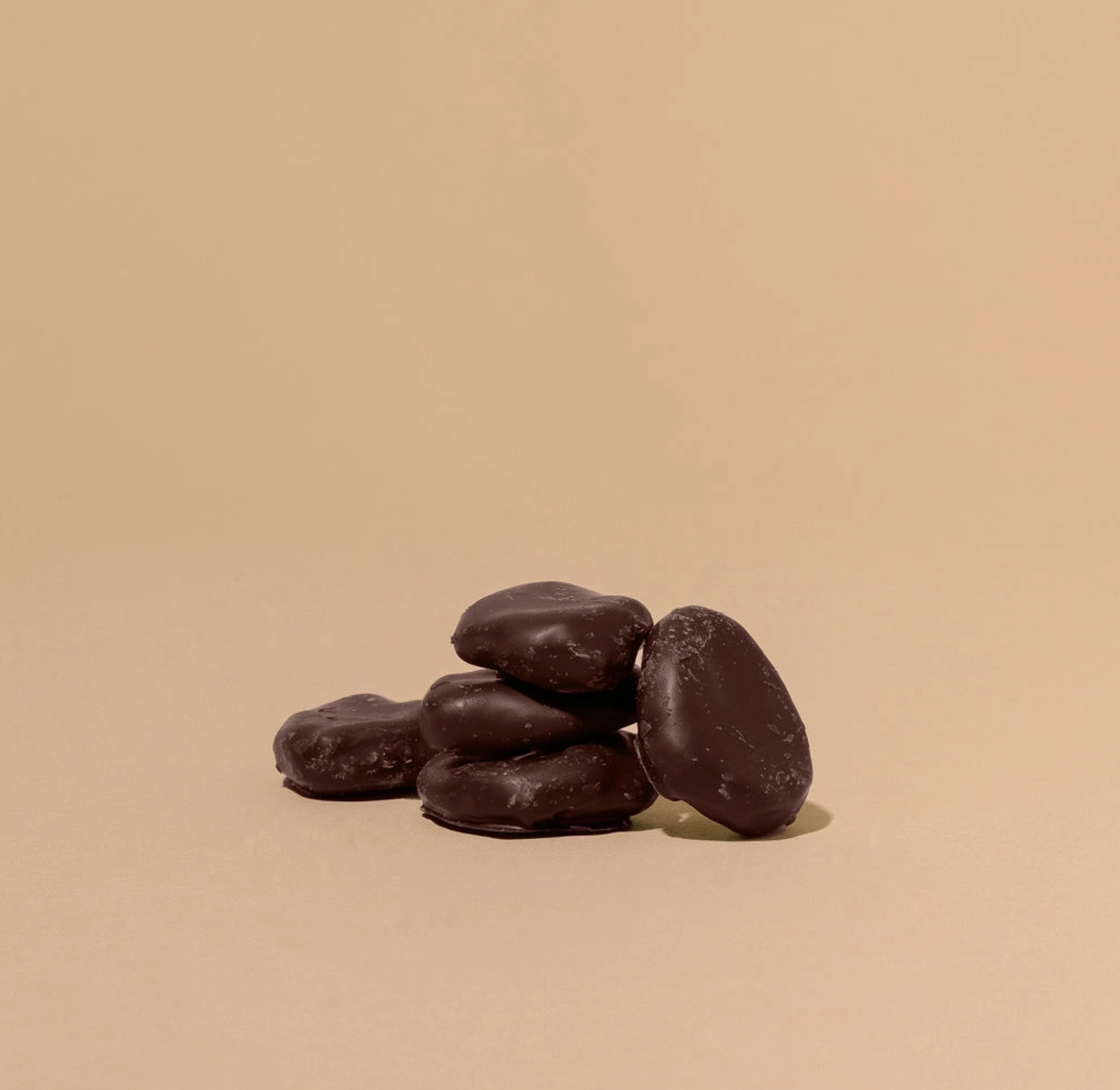 Stack of dark chocolate candies on a beige background