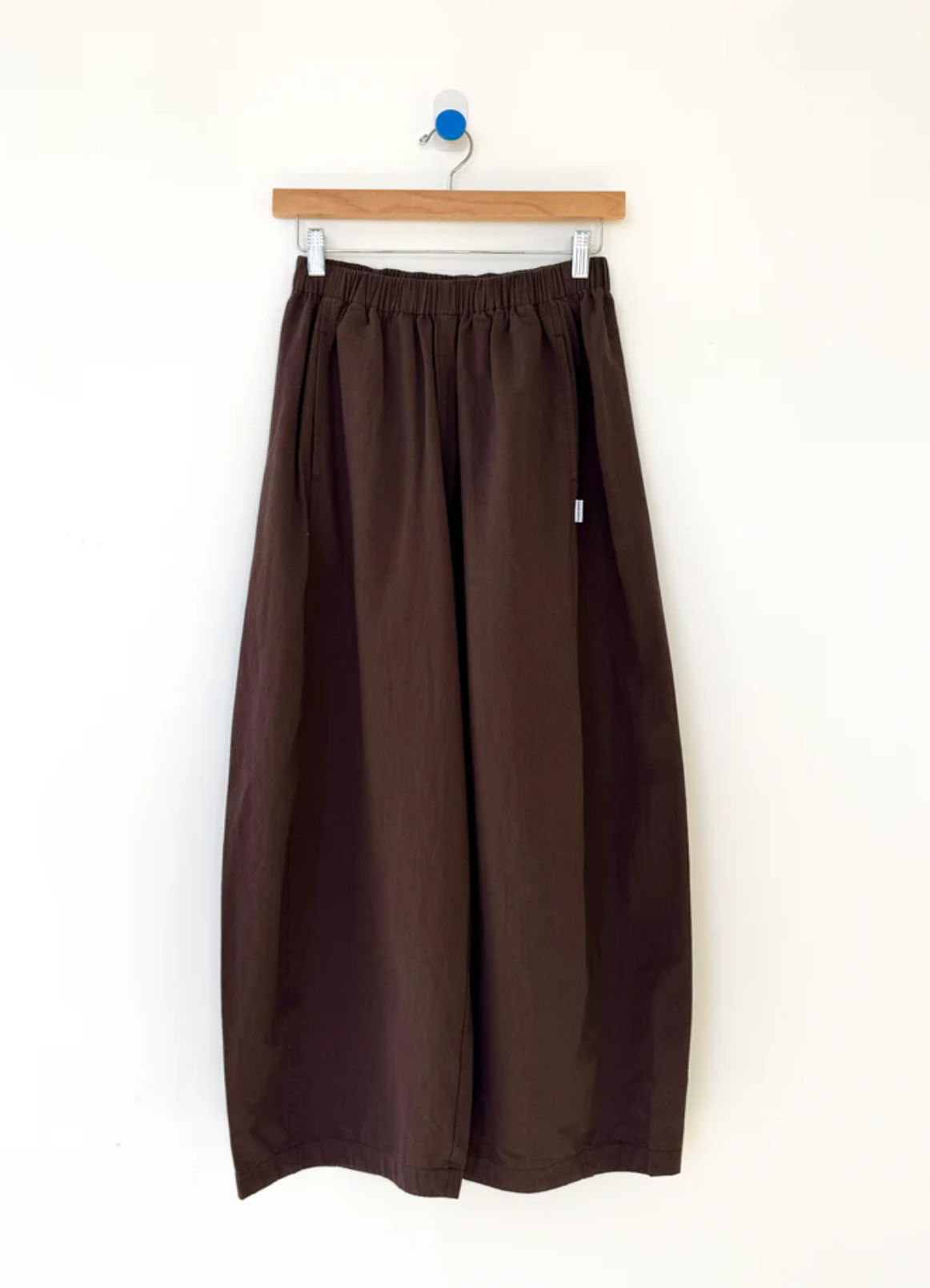 Brown wide-leg pants on a hanger against a white background