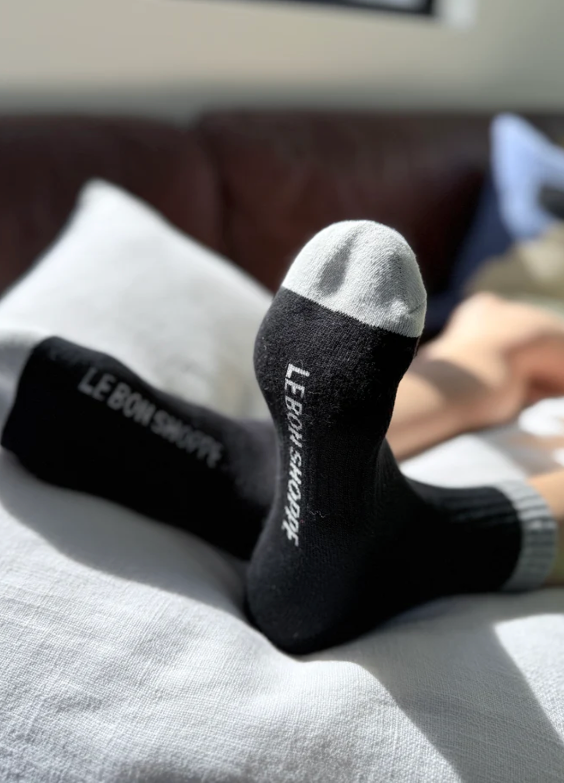 Black socks with white accents and 'Le Bon Shoppe' branding on a gray surface.