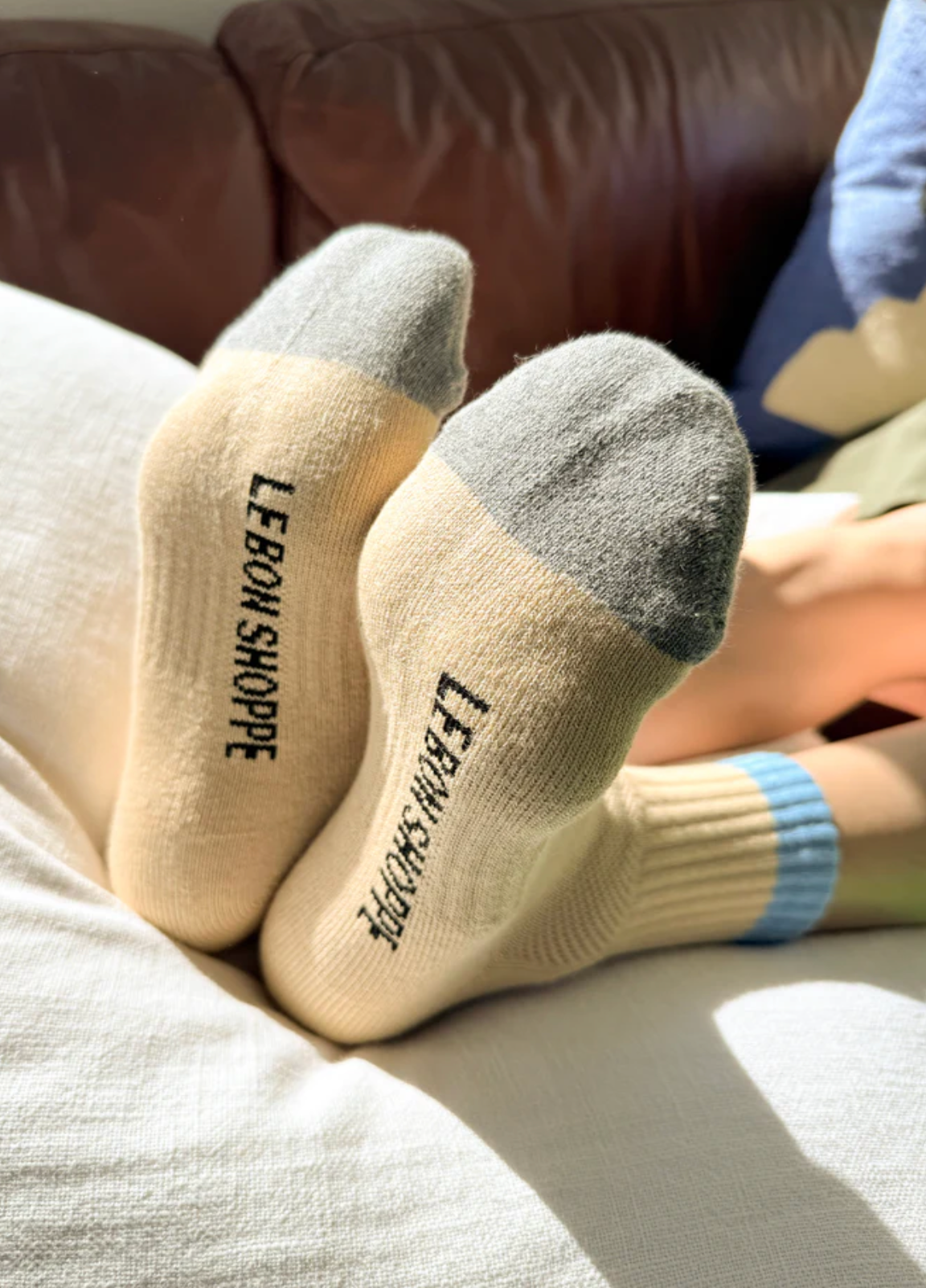 Beige socks with 'LEBON SHOPPE' branding on a couch.