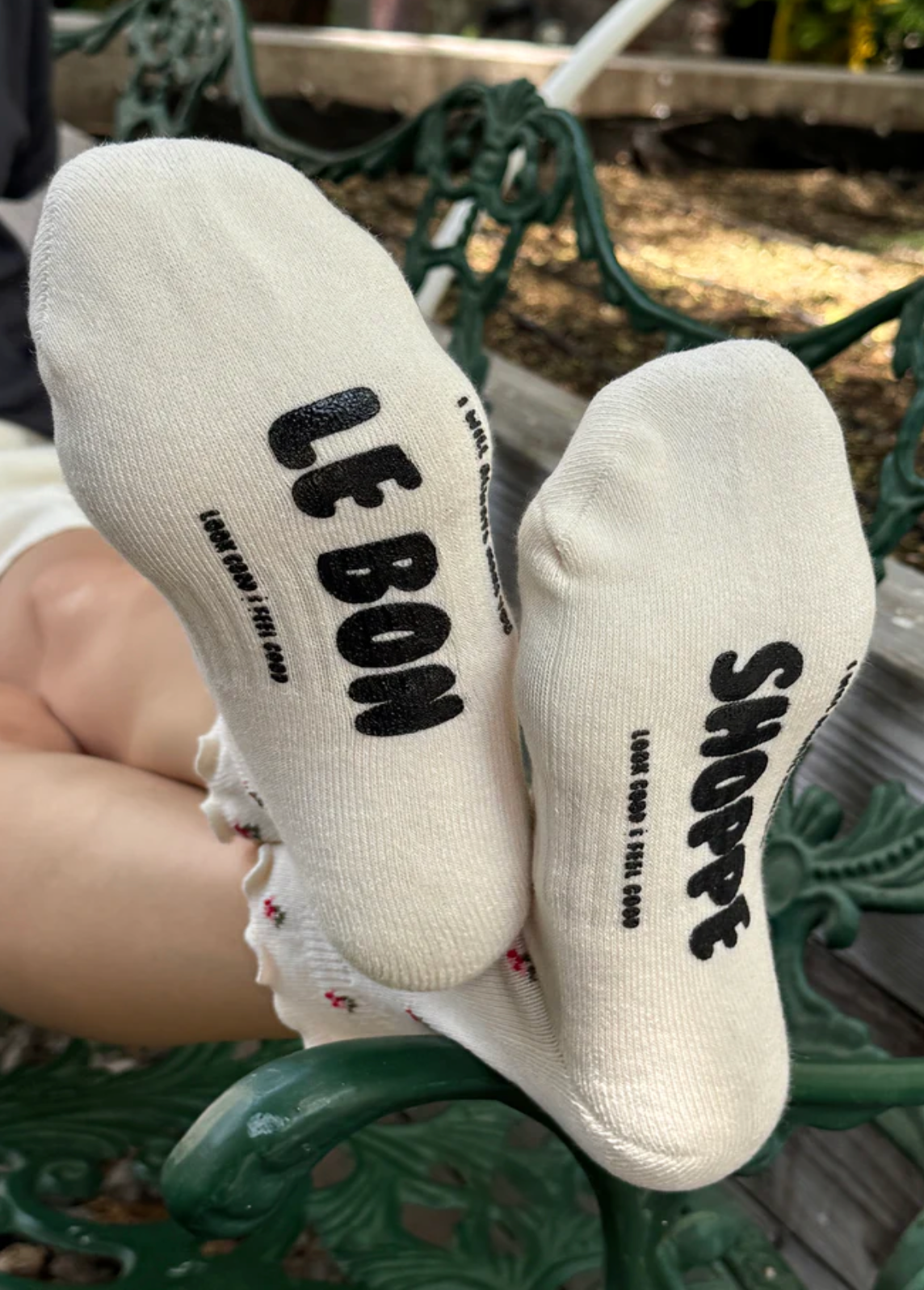 White socks with black text on a green metal bench.