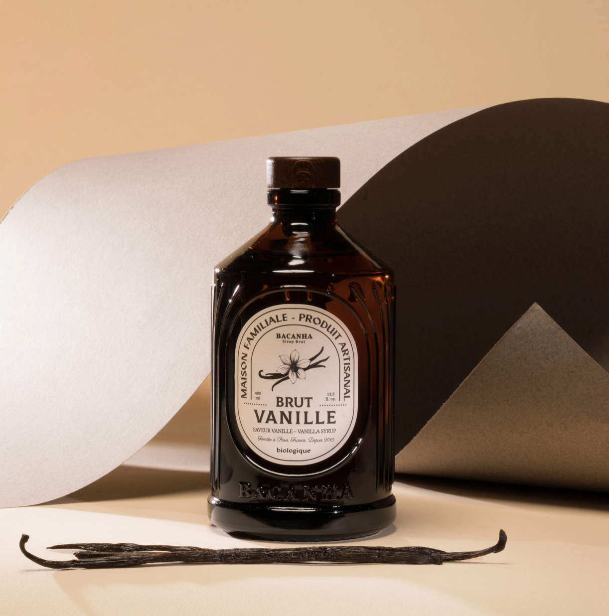 brown glass bottle with real vanilla bean and beige background