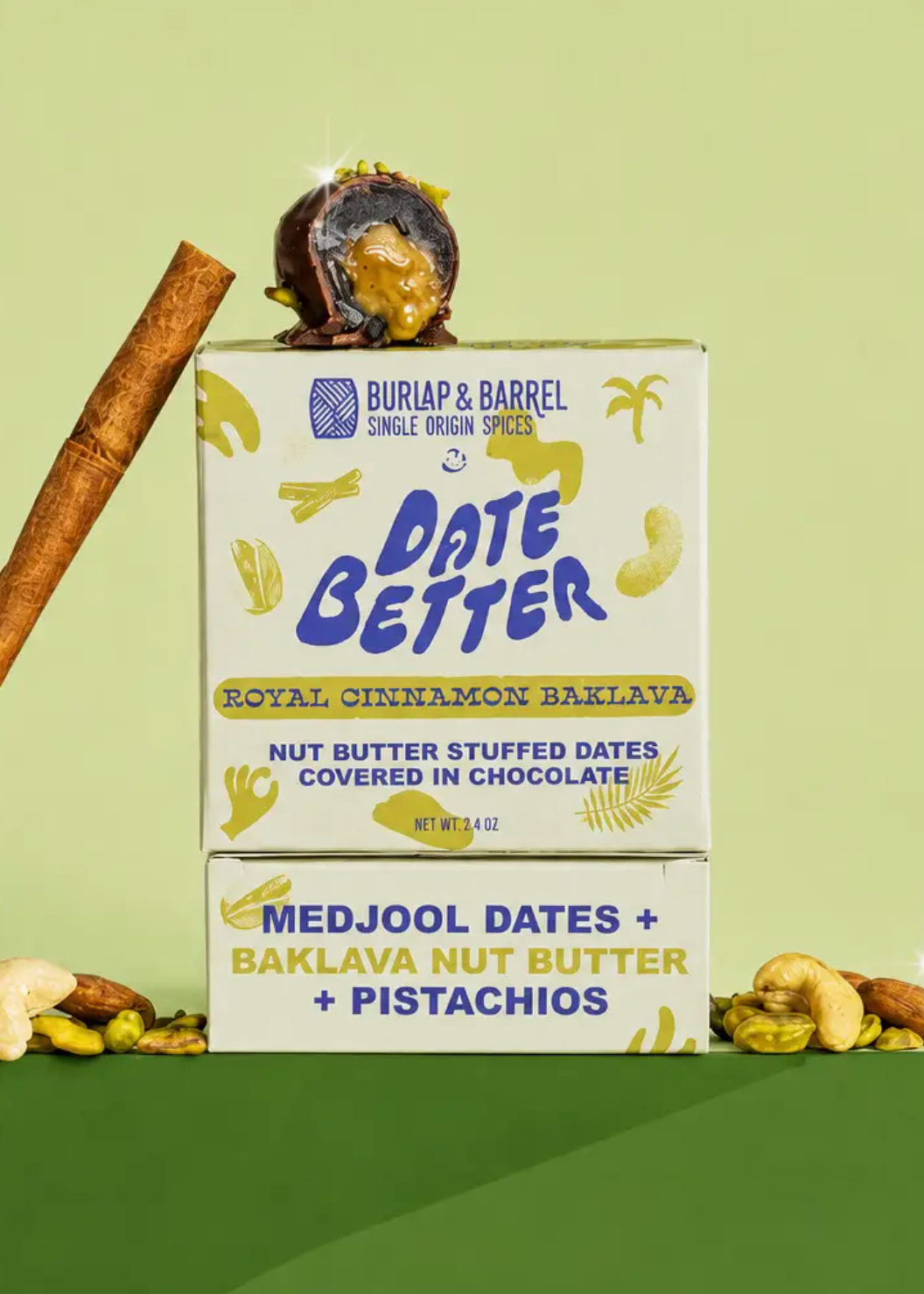 Buriap & Barrel Date Better Royal Cinnamon Baklava product box shown on a light green background with a cinnamon stick, a chocolate-dipped date, and nuts arranged around it.