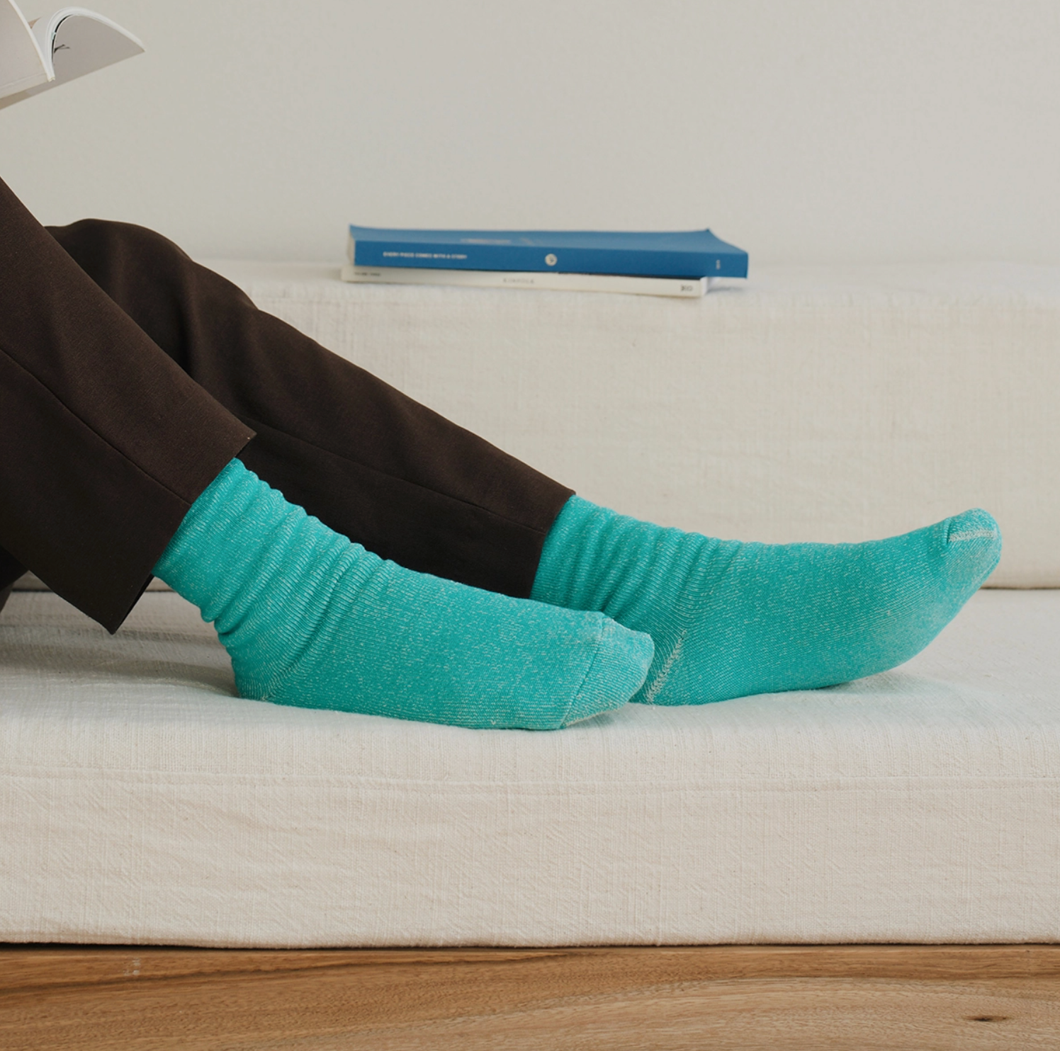 turquoise socks on a model sitting on a white futon
