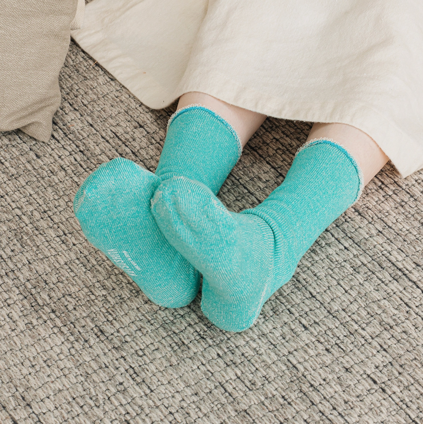 turquoise socks on a model sitting on a gray rug