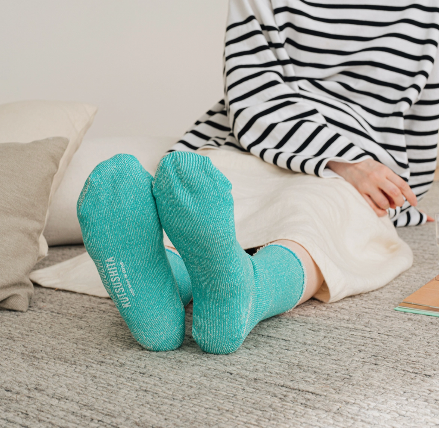 turquoise socks on a model sitting on a gray rug