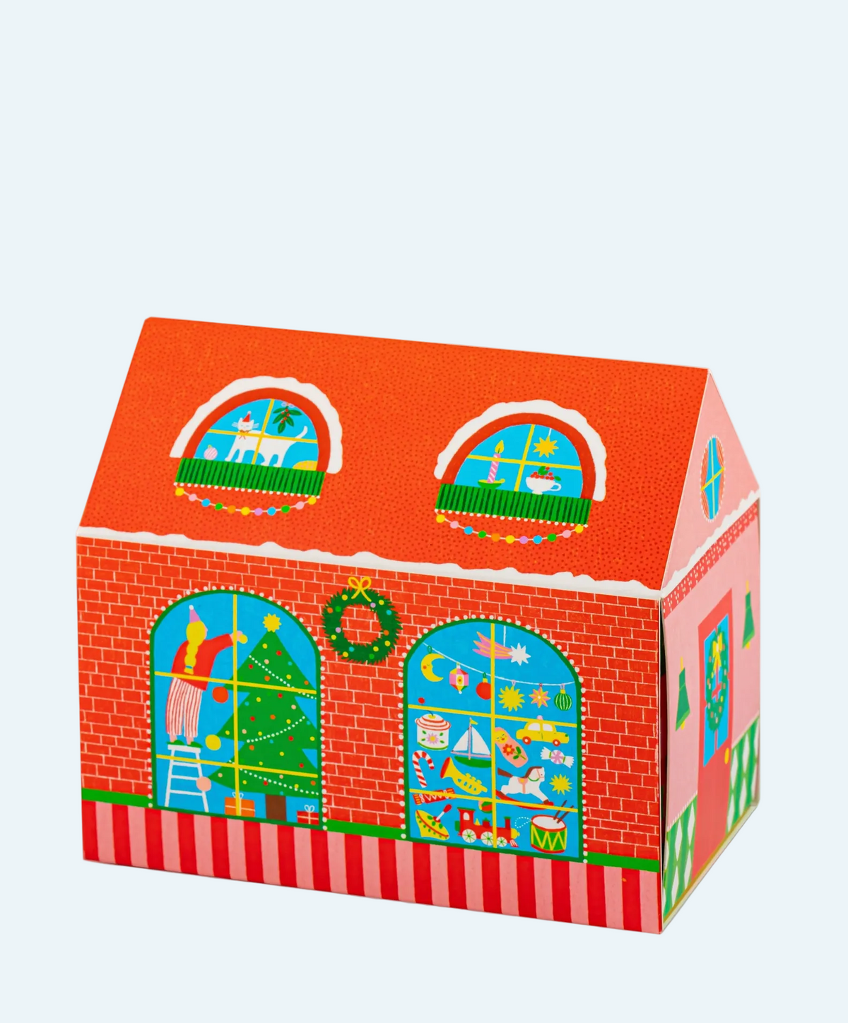 A Christmas-themed house-shaped box with red brick walls, a red-orange roof, green trim, and colorful holiday decorations visible through arched windows, shown on a white background within a browser screenshot.