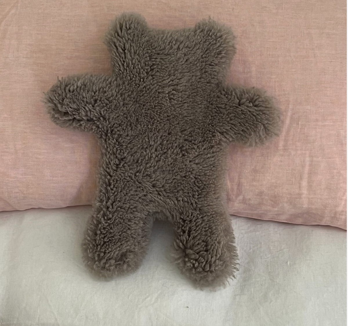teddy on a pink pillow on a white bed