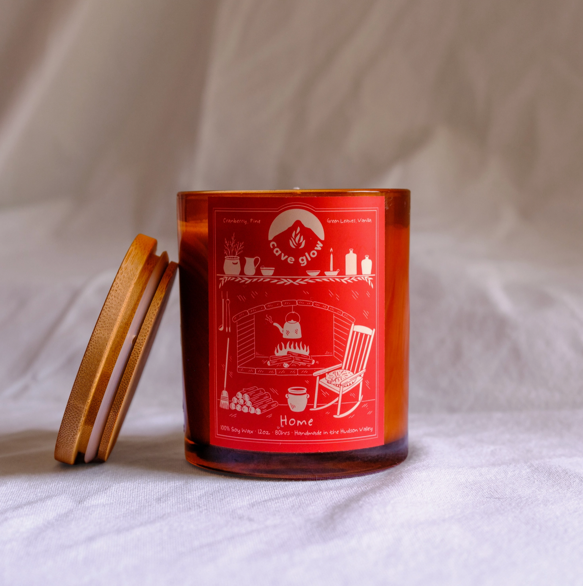 amber glass candle with wooden lid and red label with drawing of "home," a fire place with tea pot boiling, a mantle with candle and decorations, a rocking chair, broom and other little details