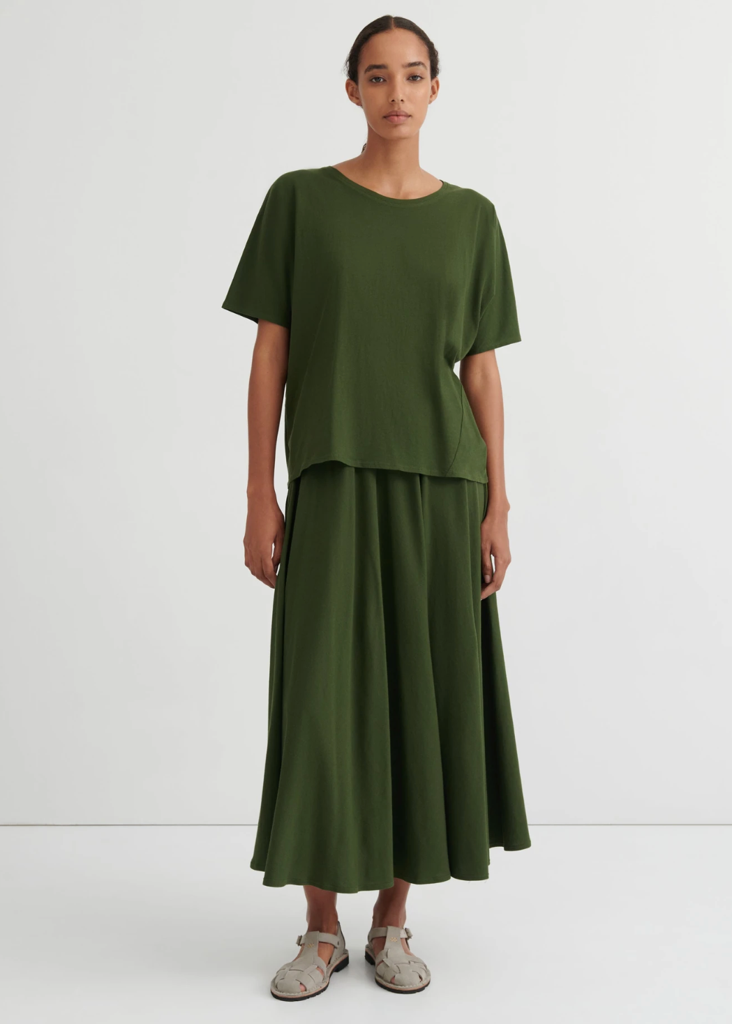 green tee on model wearing matching green skirt and off white shoes