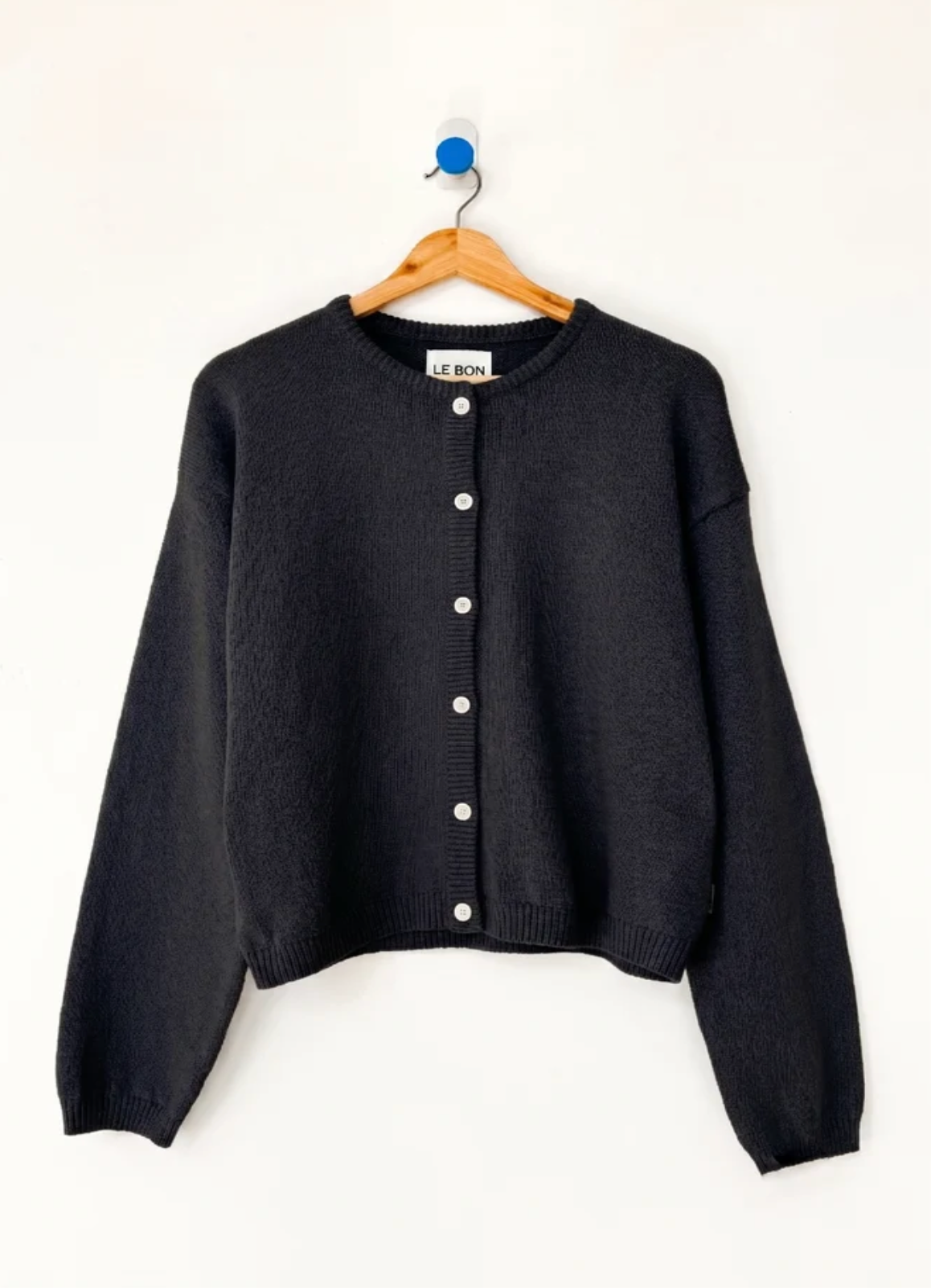 black cardigan on wooden hanger