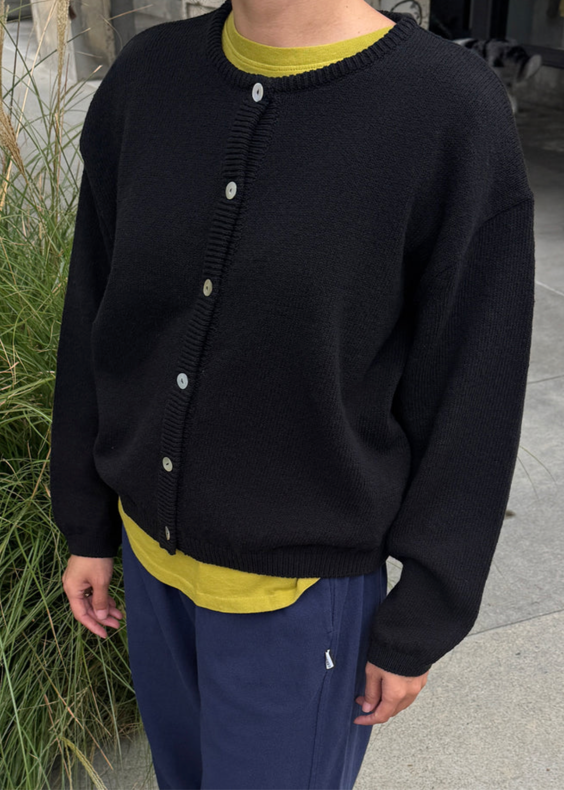 model wearing black cardigan with neon yellow underneath and navy sweatpants