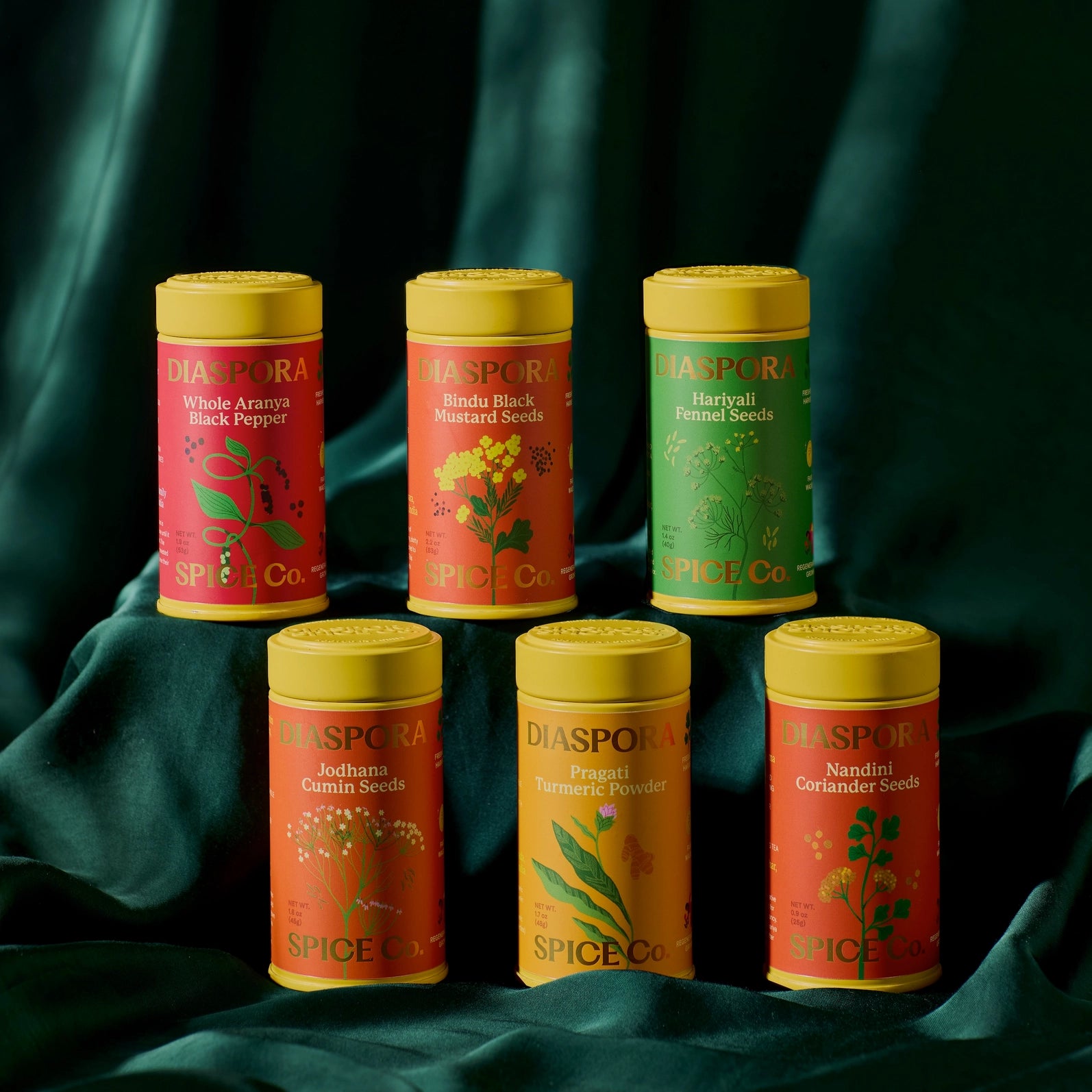 Collection of Diaspora Spice Co spice tins on a dark green fabric background