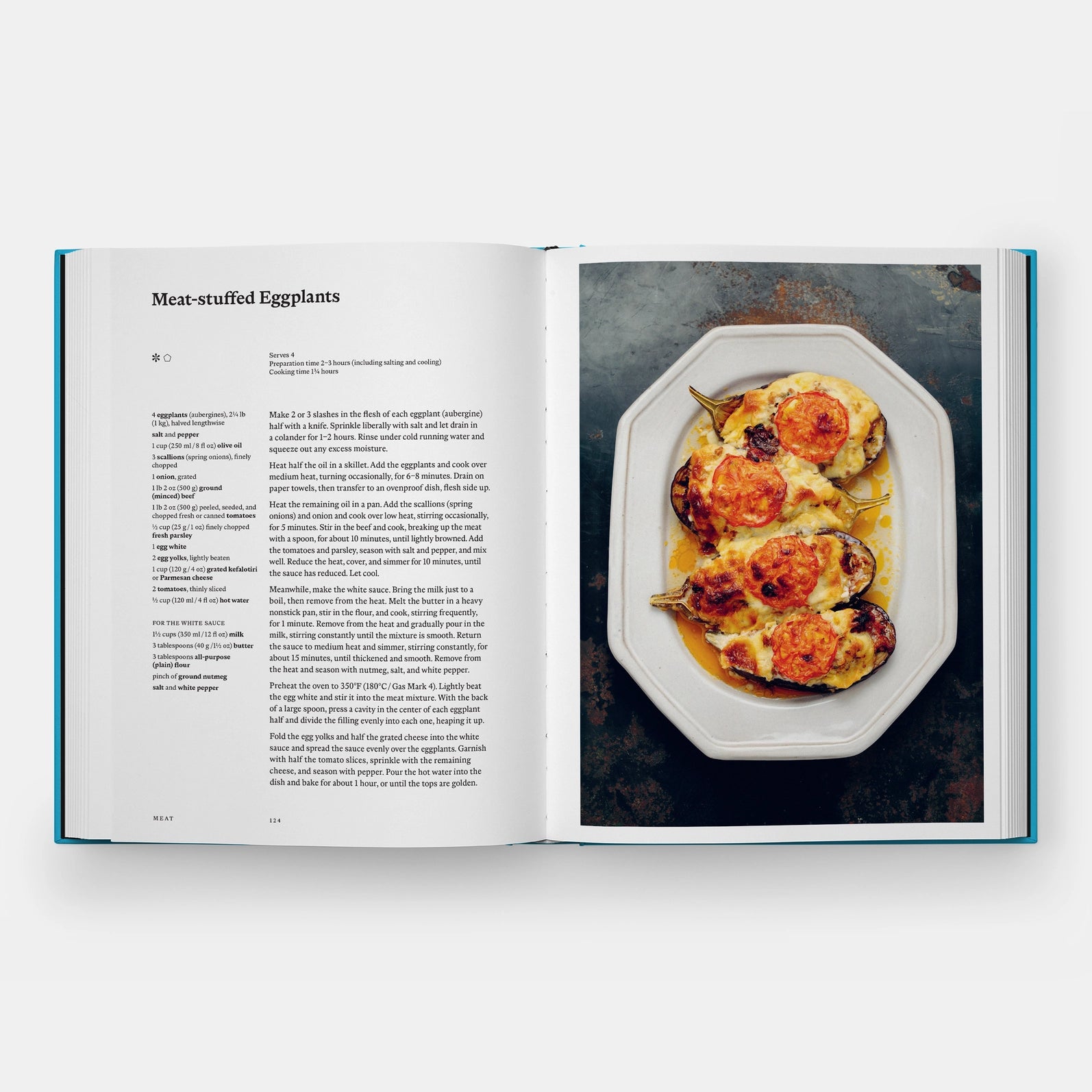 Open cookbook showing a recipe for meat-stuffed eggplants with an image of the dish on a white plate.