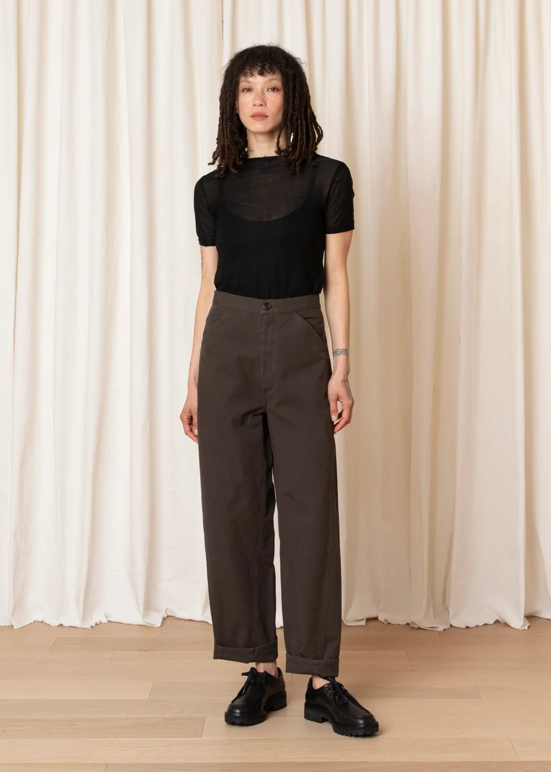 model wearing brown barrel pants and mesh black top and black shoes