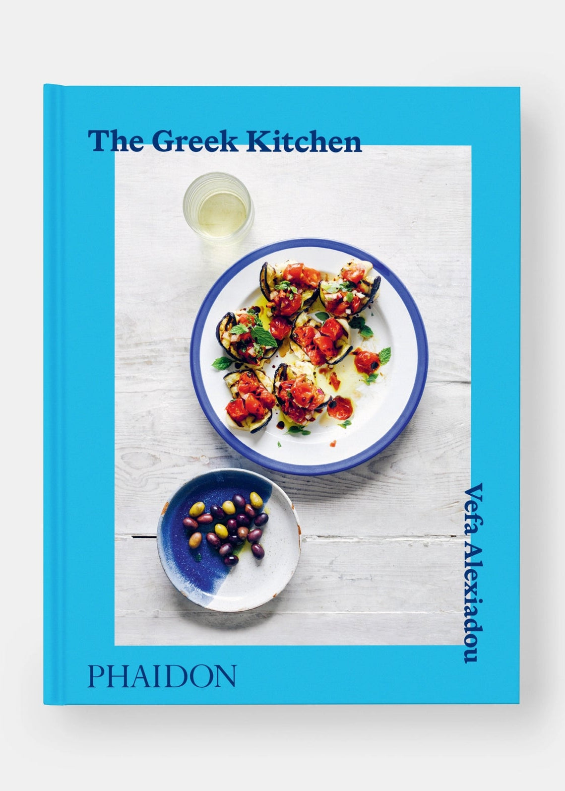 Book cover of 'The Greek Kitchen' by Phaidon with a dish and wine on a white background