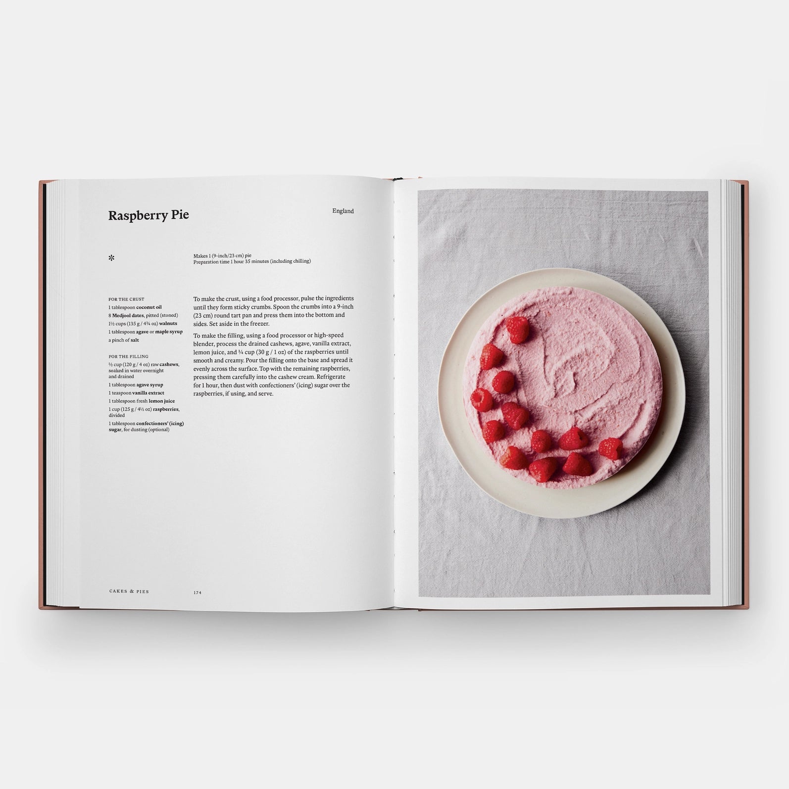 Open cookbook showing a recipe for raspberry pie with a pink dessert on a white background