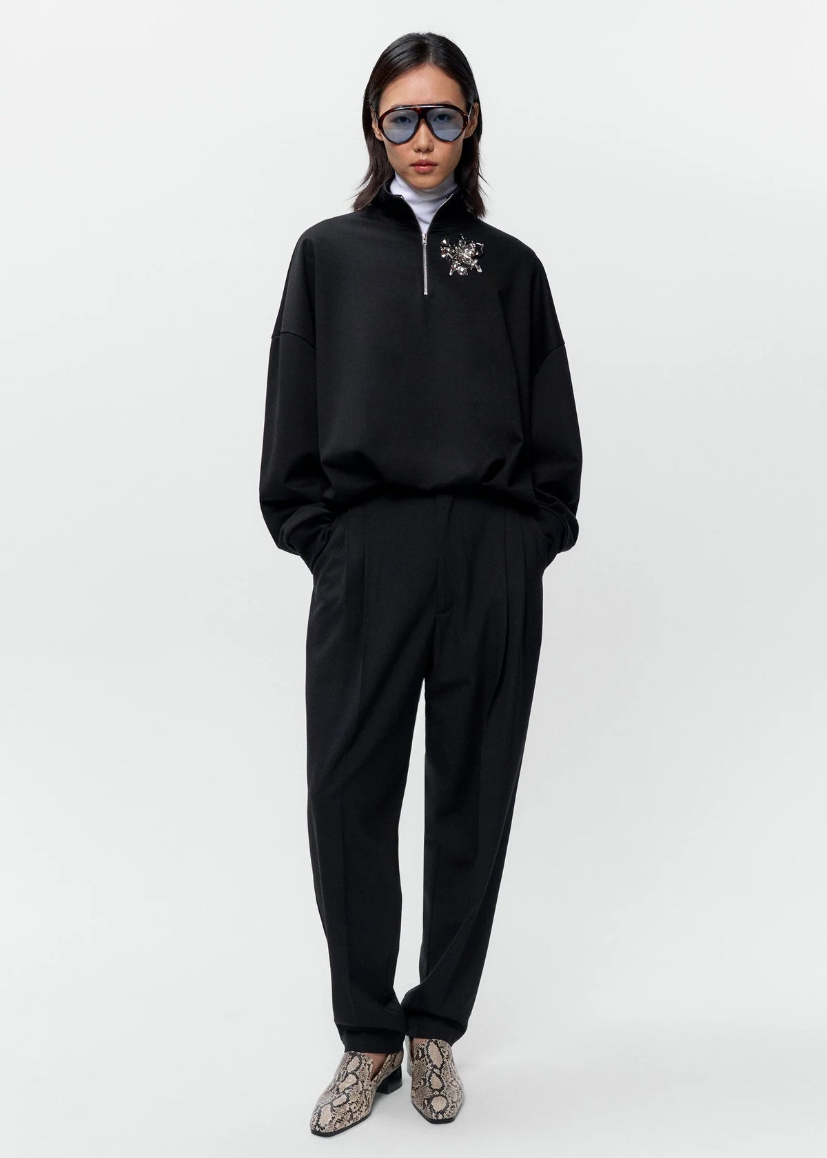 Person wearing a black outfit with sunglasses on a white background