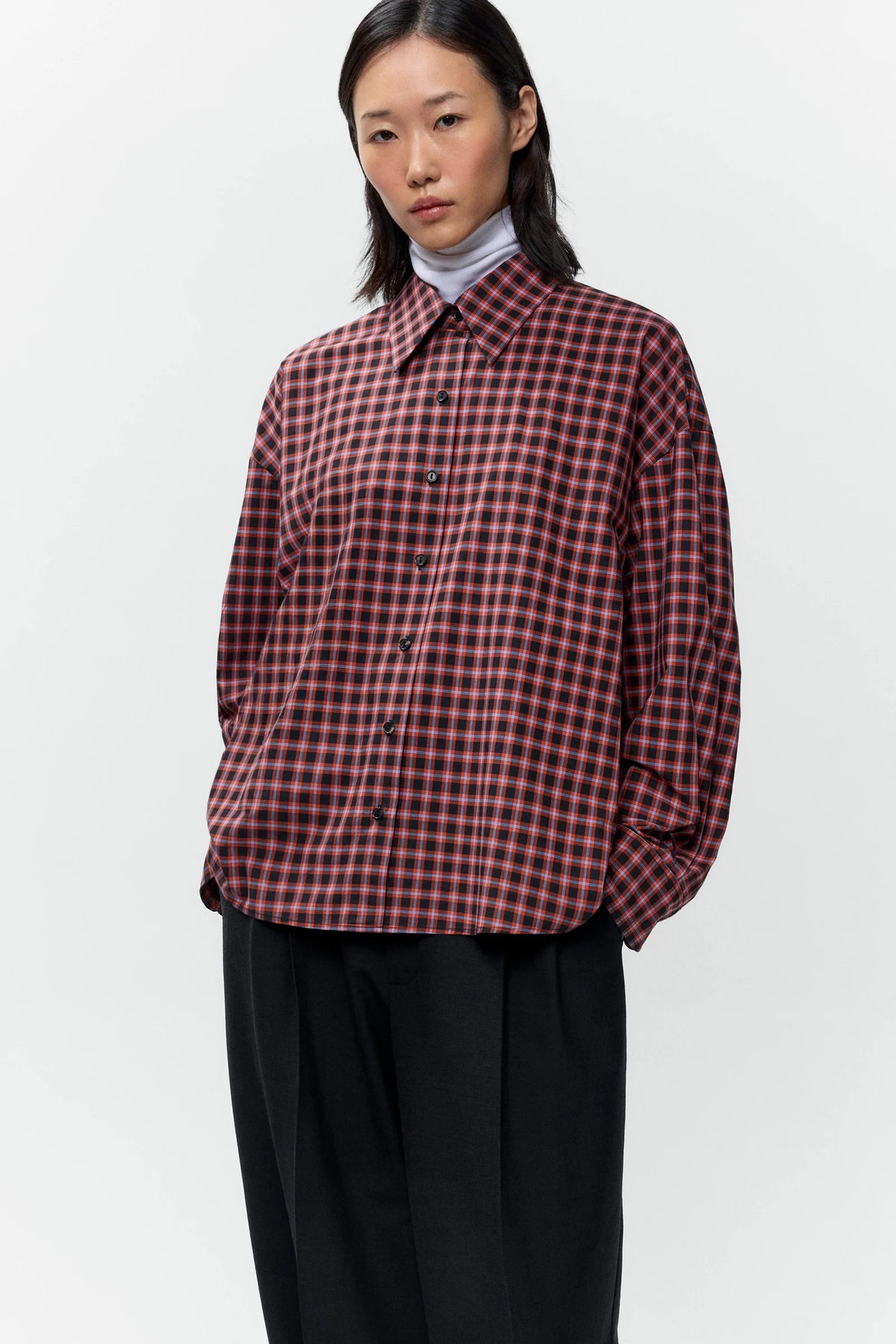Person wearing a red and black checkered shirt on a white background