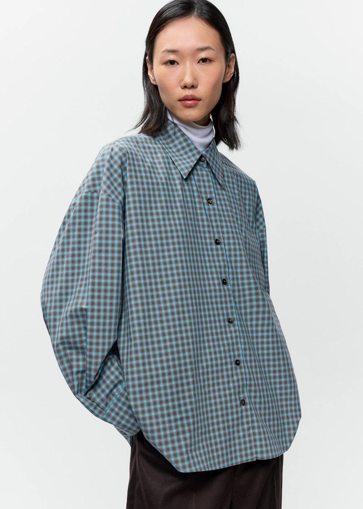 Person wearing a green and blue checkered shirt on a white background
