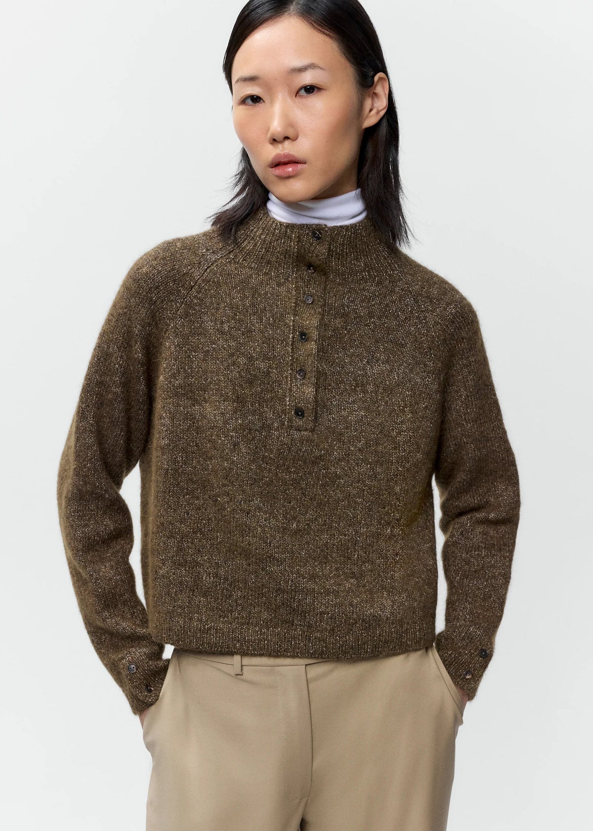 Woman wearing a brown knitted sweater with buttons on a white background