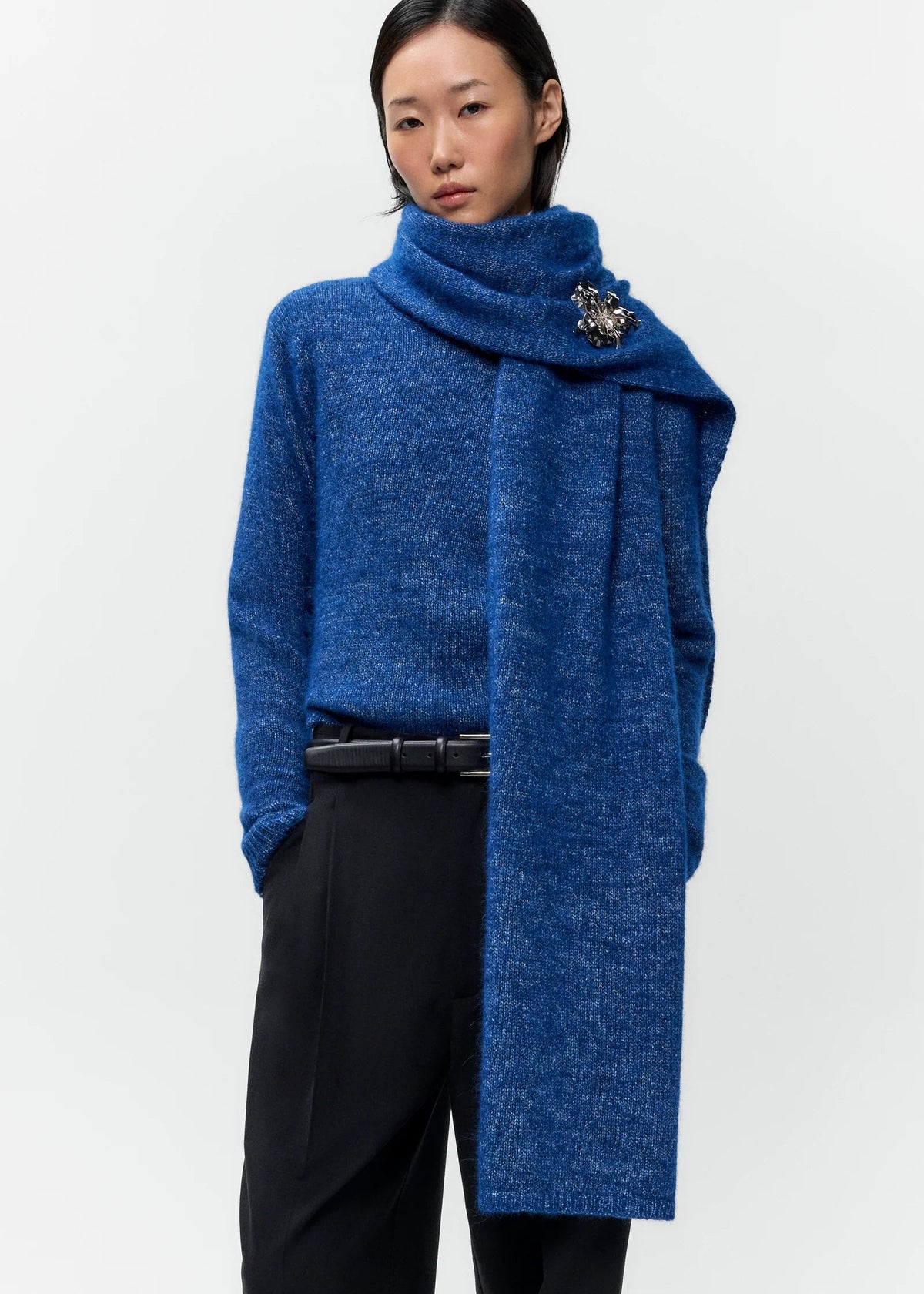 cobalt blue scarf secured with pin on a model wearing a matching sweater and black pants