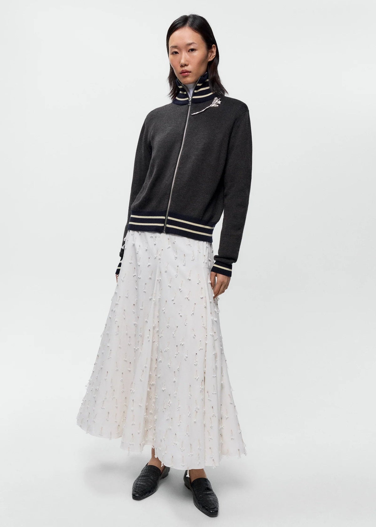 Woman wearing a black jacket with white trim and a white dress with black polka dots on a white background