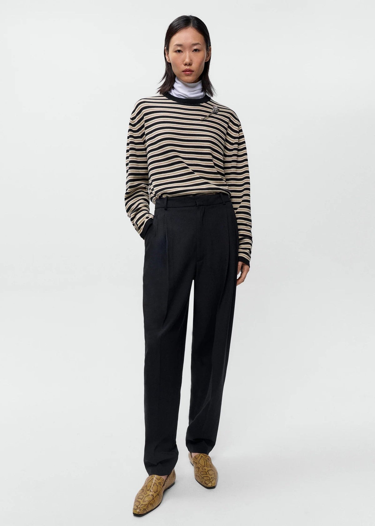 Person wearing a striped sweater and black pants on a white background