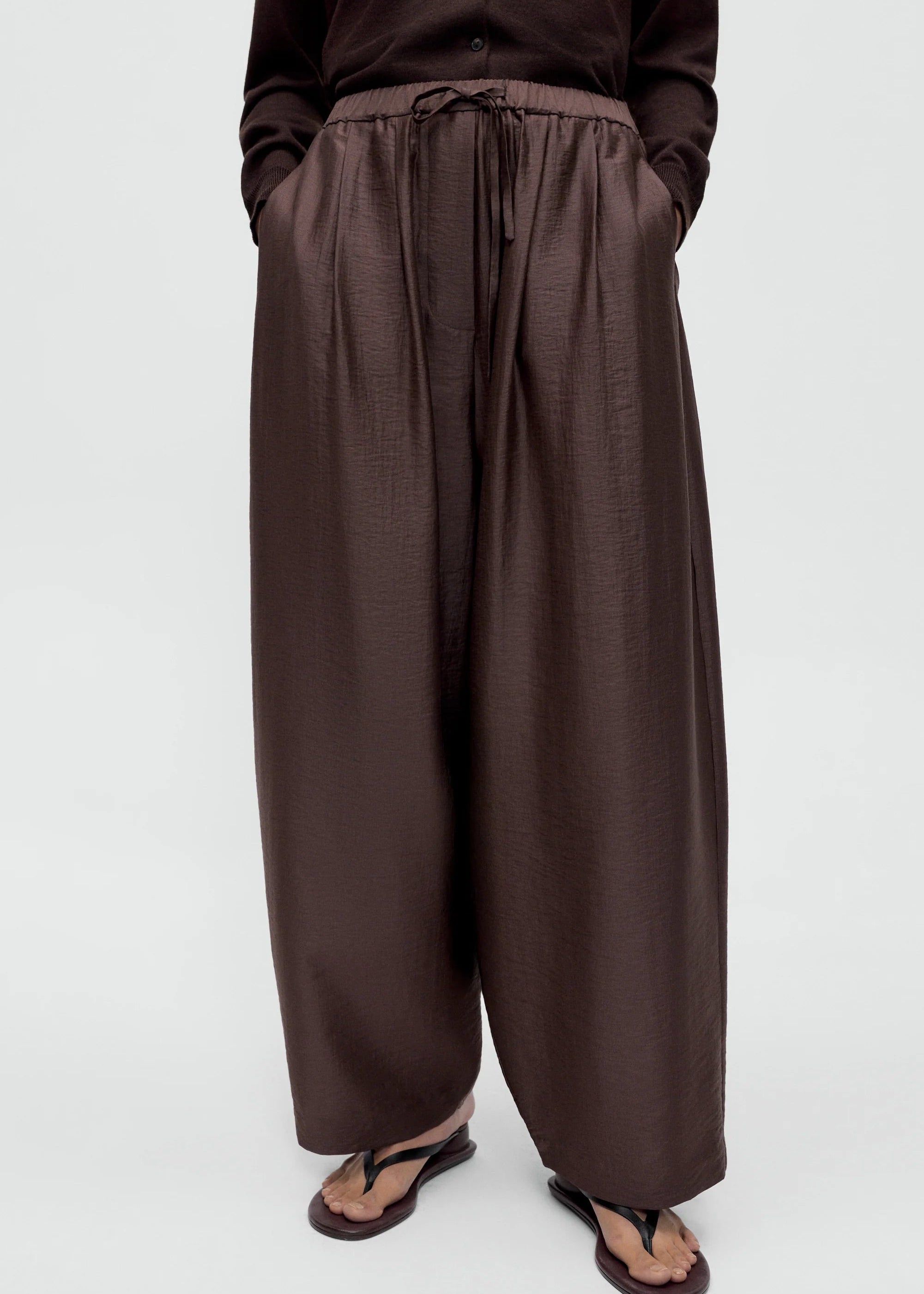 Person wearing brown wide-leg pants on a white background