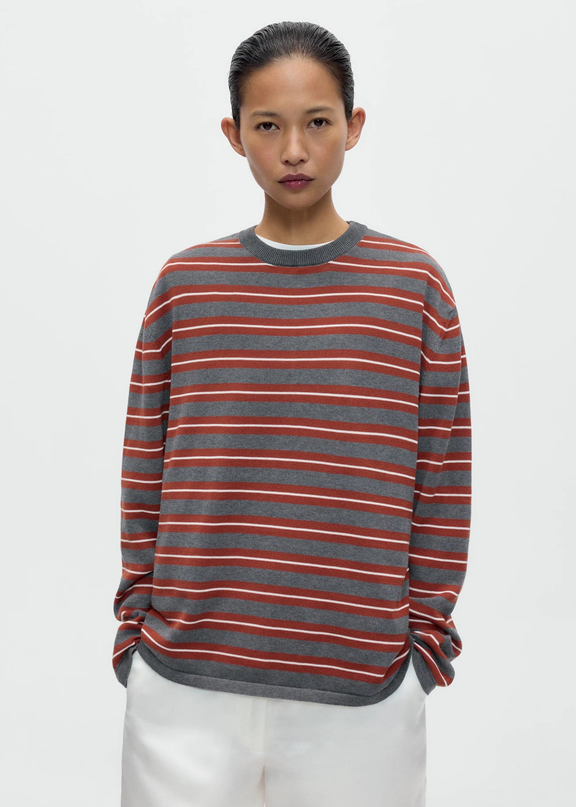 Person wearing a striped sweater with red and gray horizontal lines on a white background