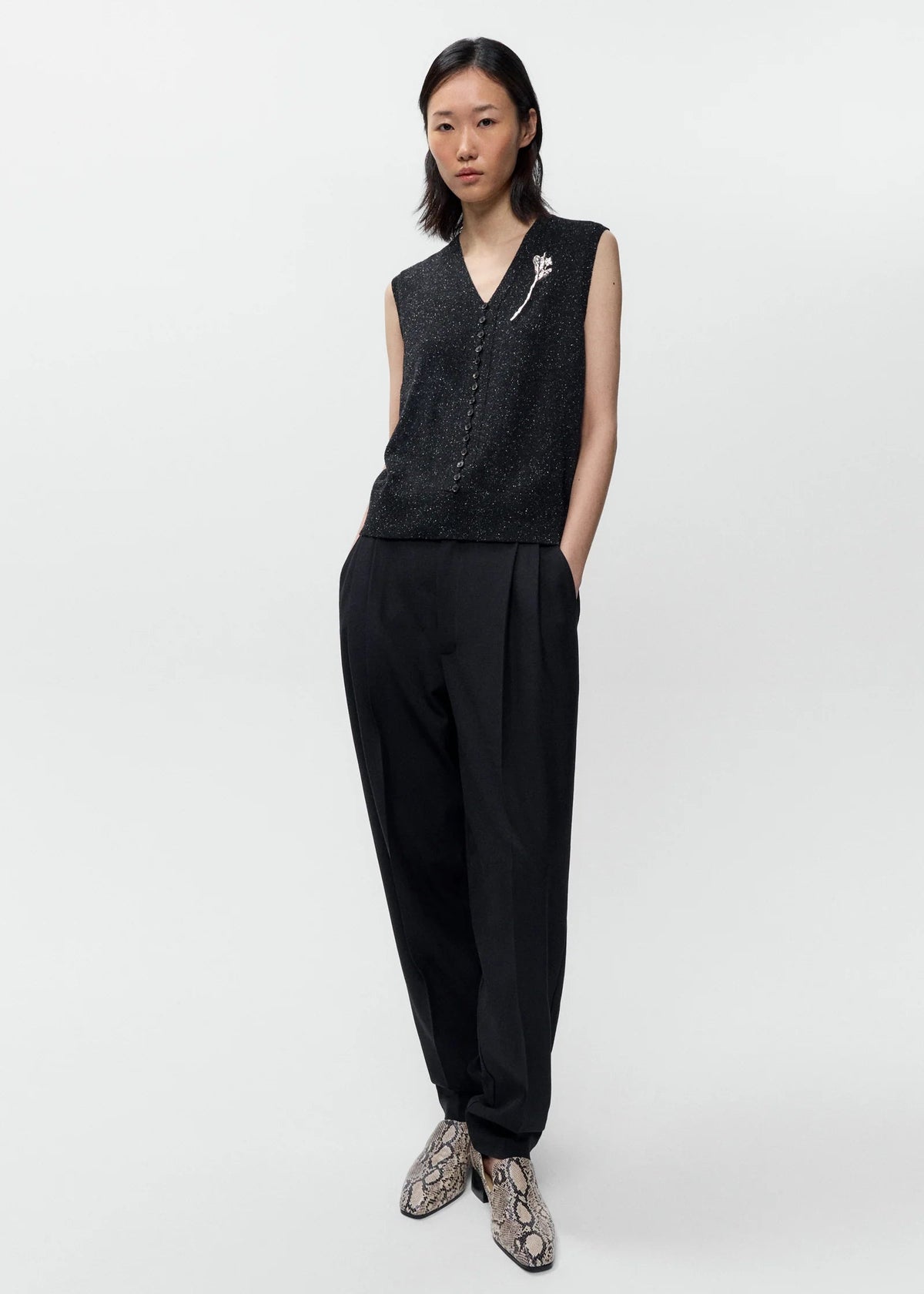 Woman wearing a black sleeveless top and pants on a white background