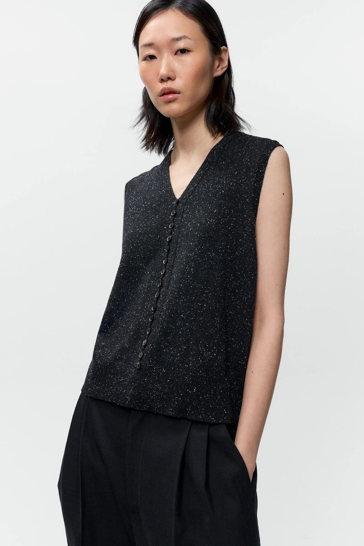 Woman wearing a black sleeveless top and black pants on a white background