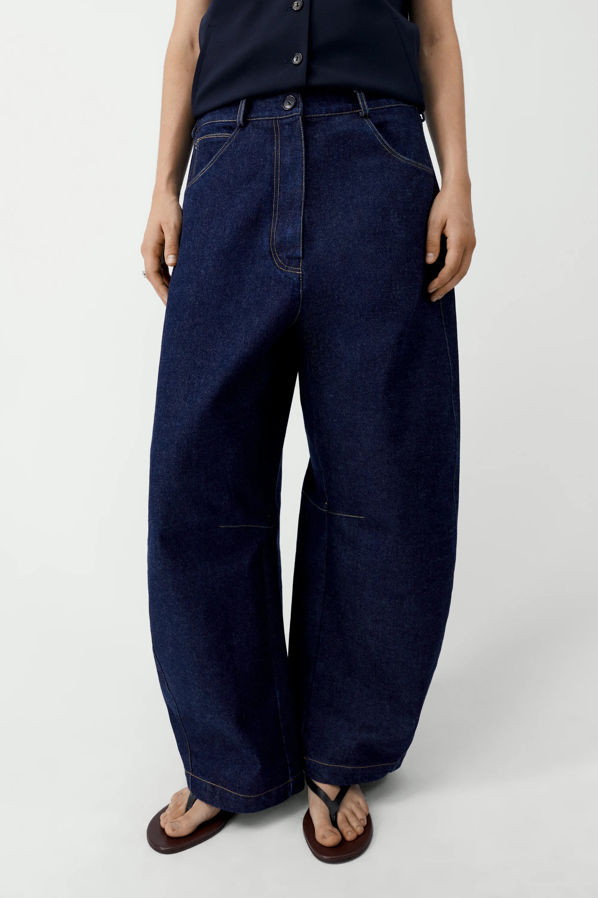Person wearing dark blue wide-leg jeans on a white background