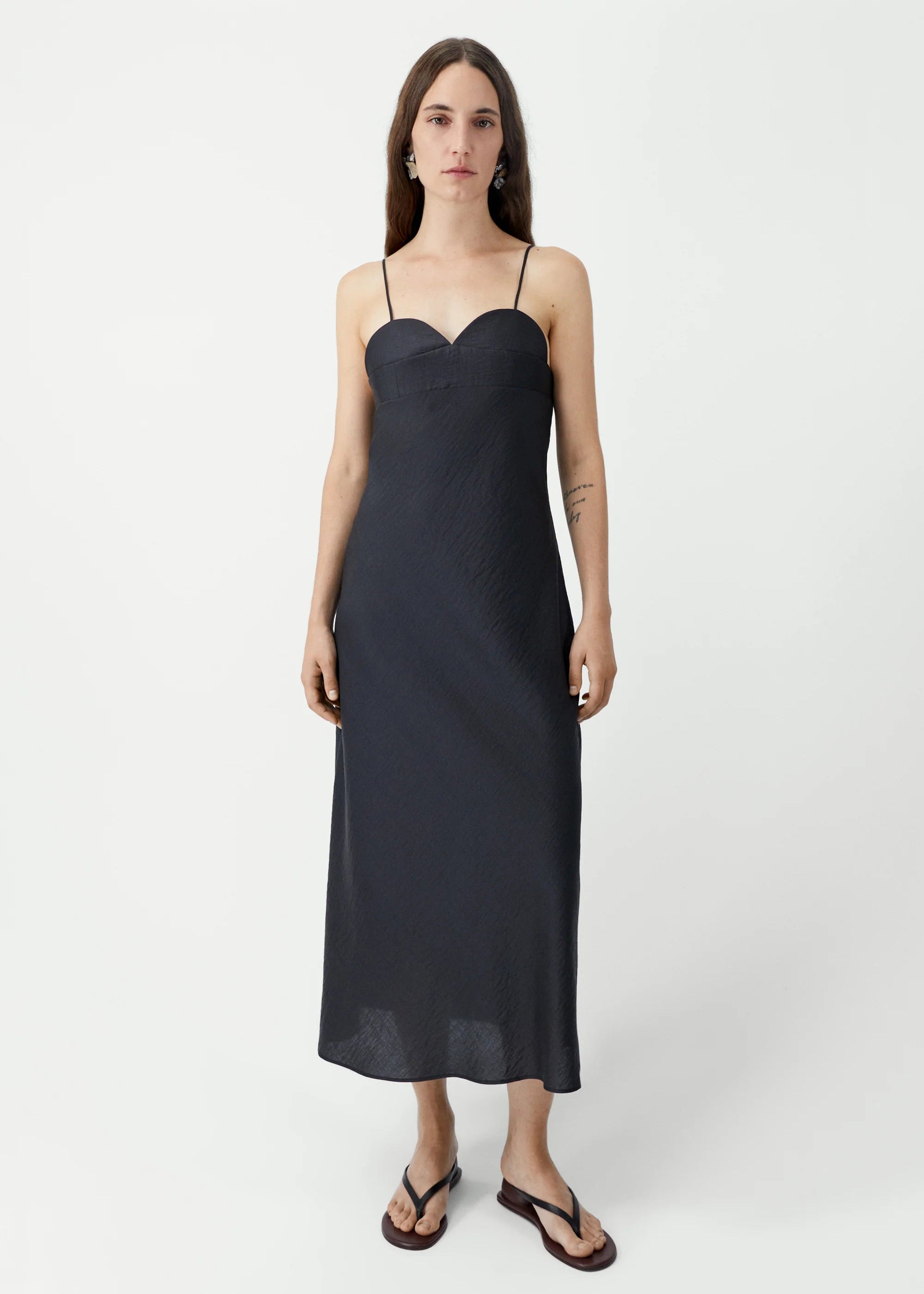 Woman wearing a black slip dress on a white background