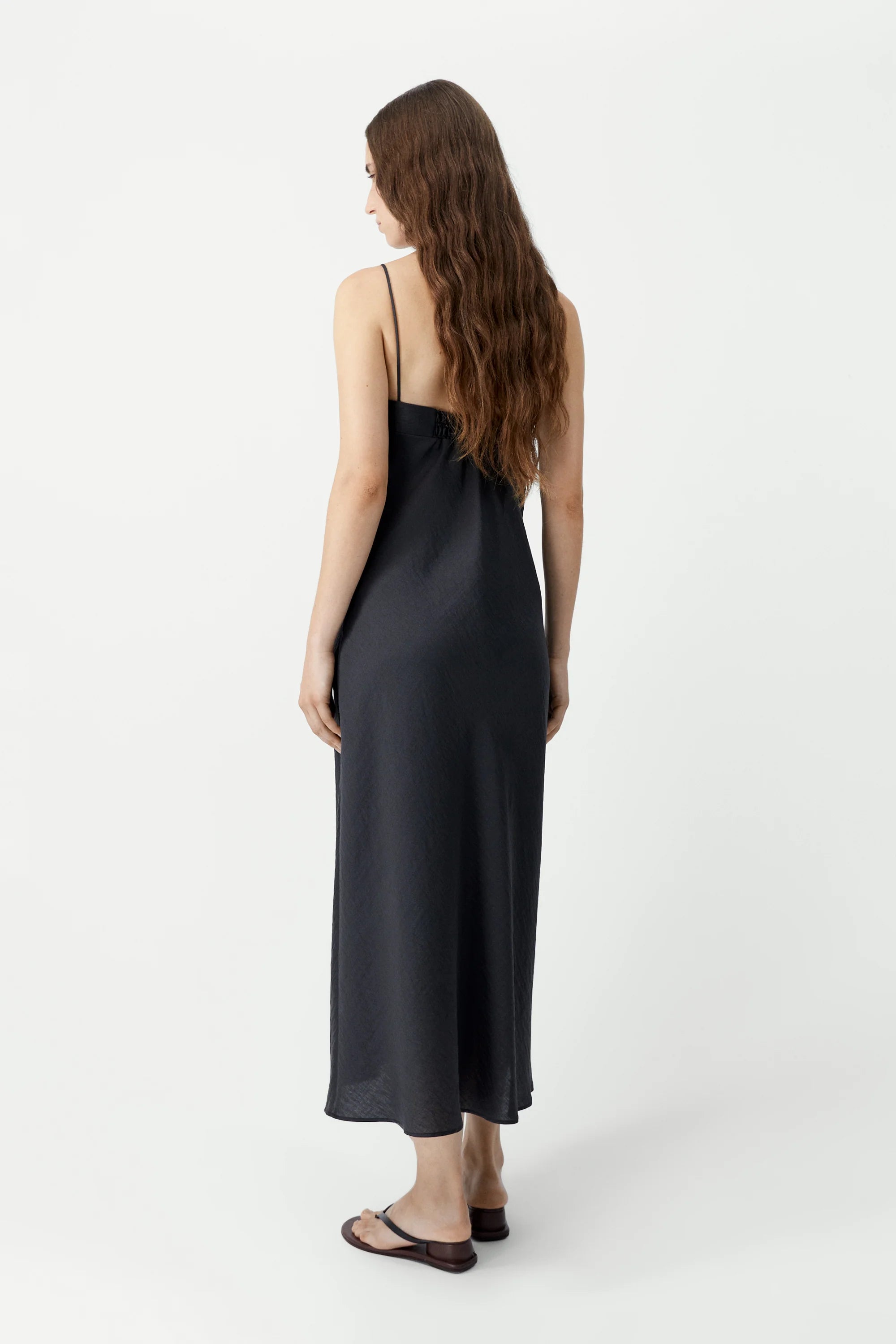 Woman wearing a black slip dress on a white background
