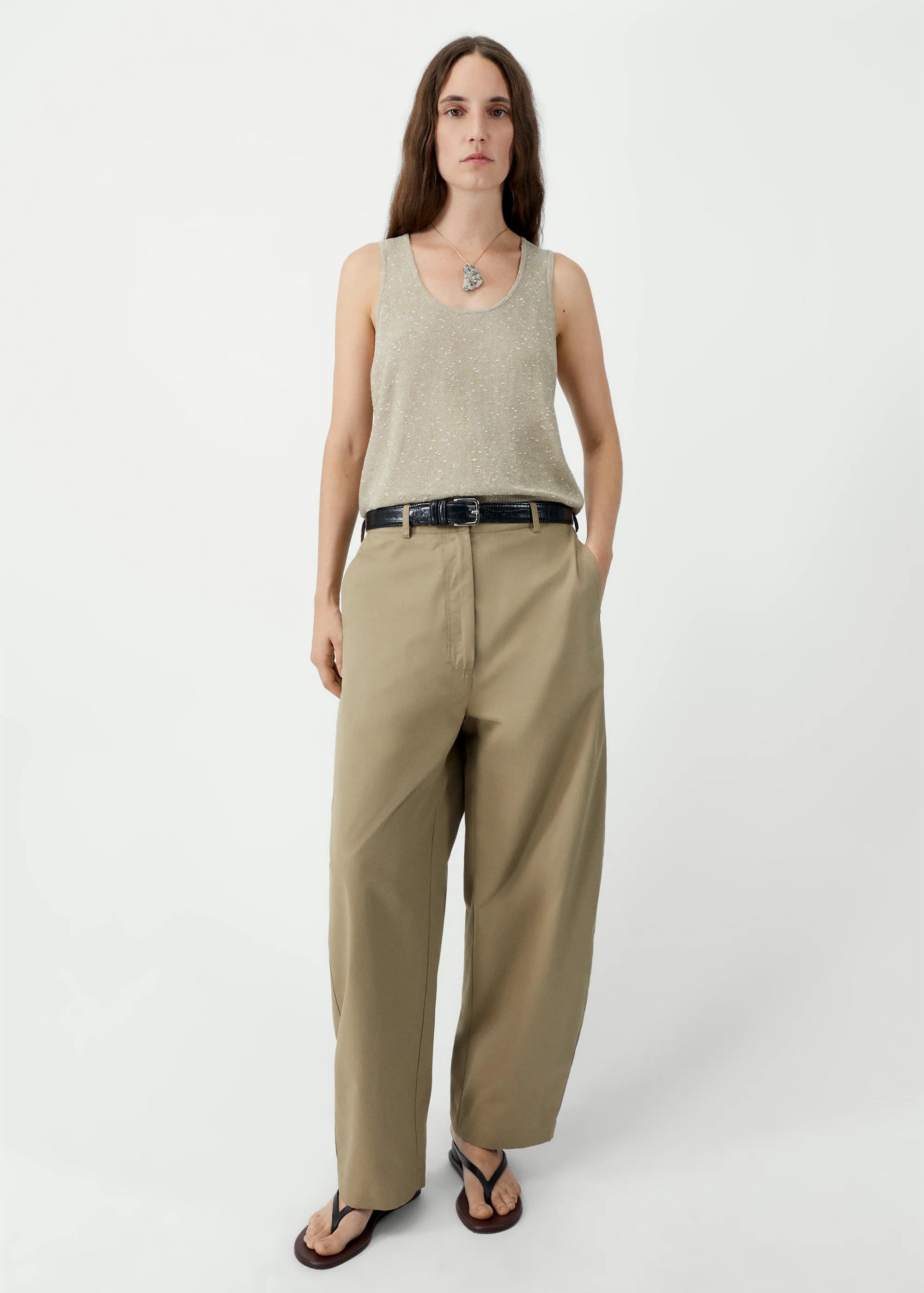 Woman wearing a beige sleeveless top and wide-leg pants on a white background
