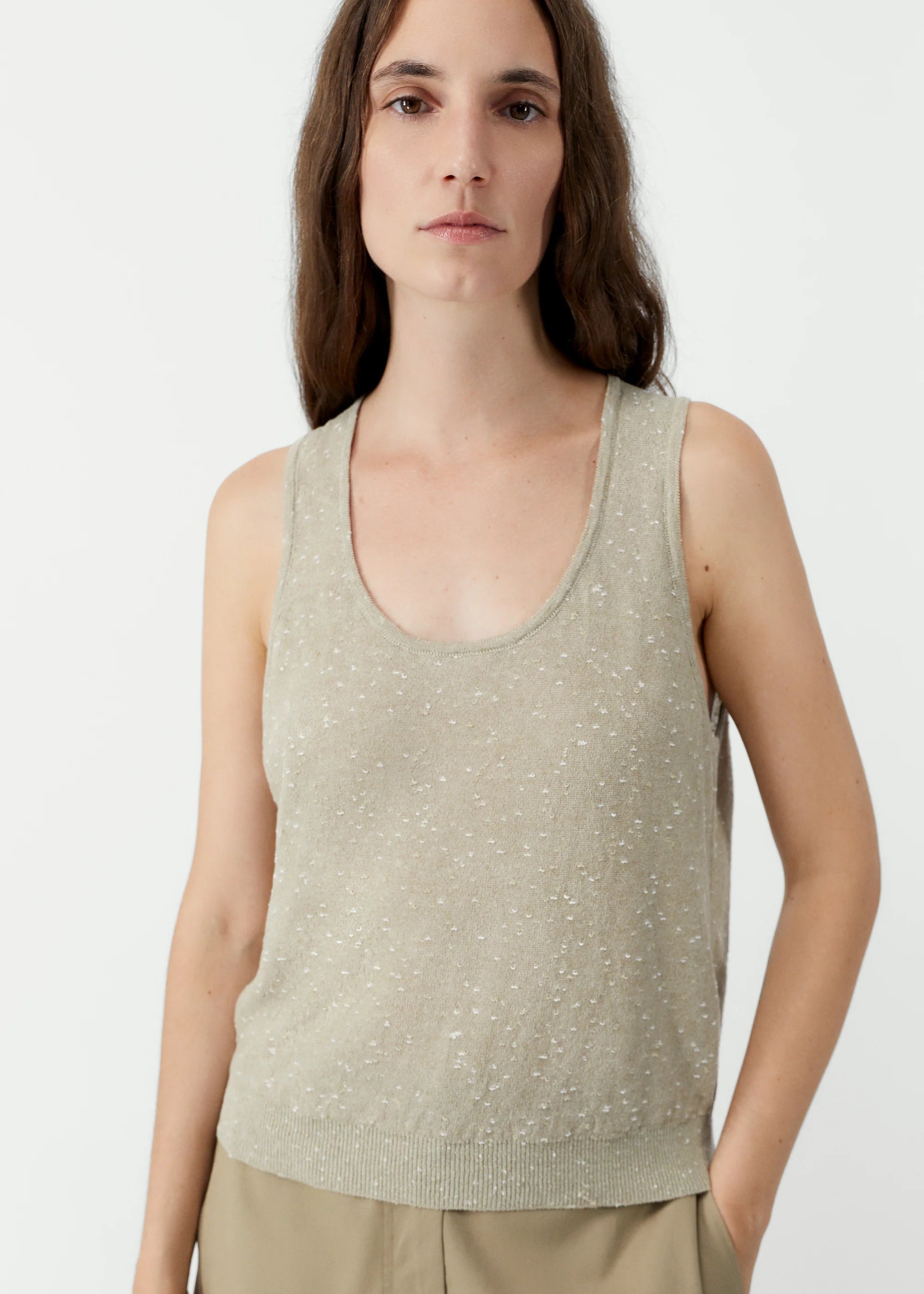 Woman wearing a light green sleeveless top against a white background
