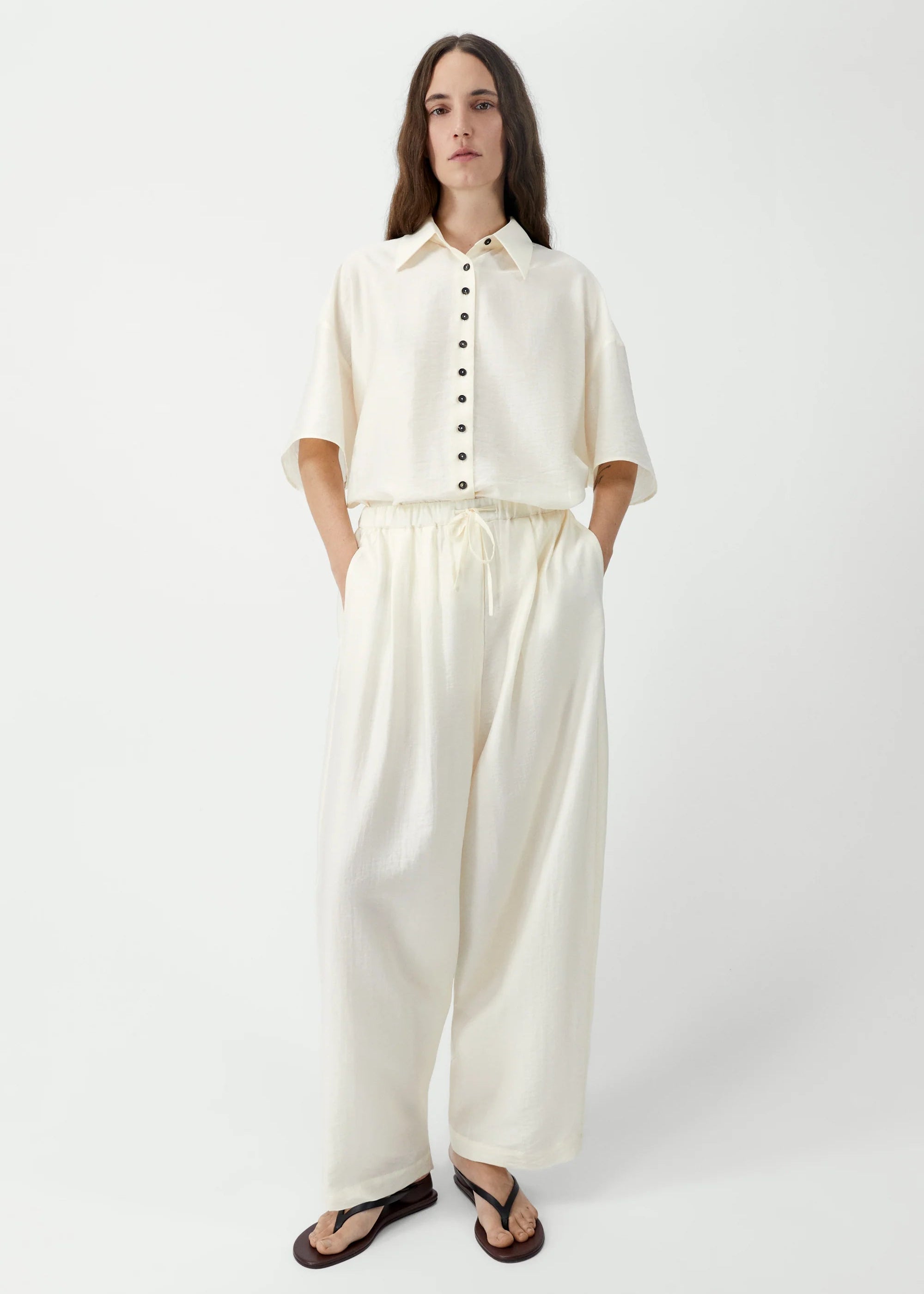 Person wearing a white shirt and wide-leg pants on a white background