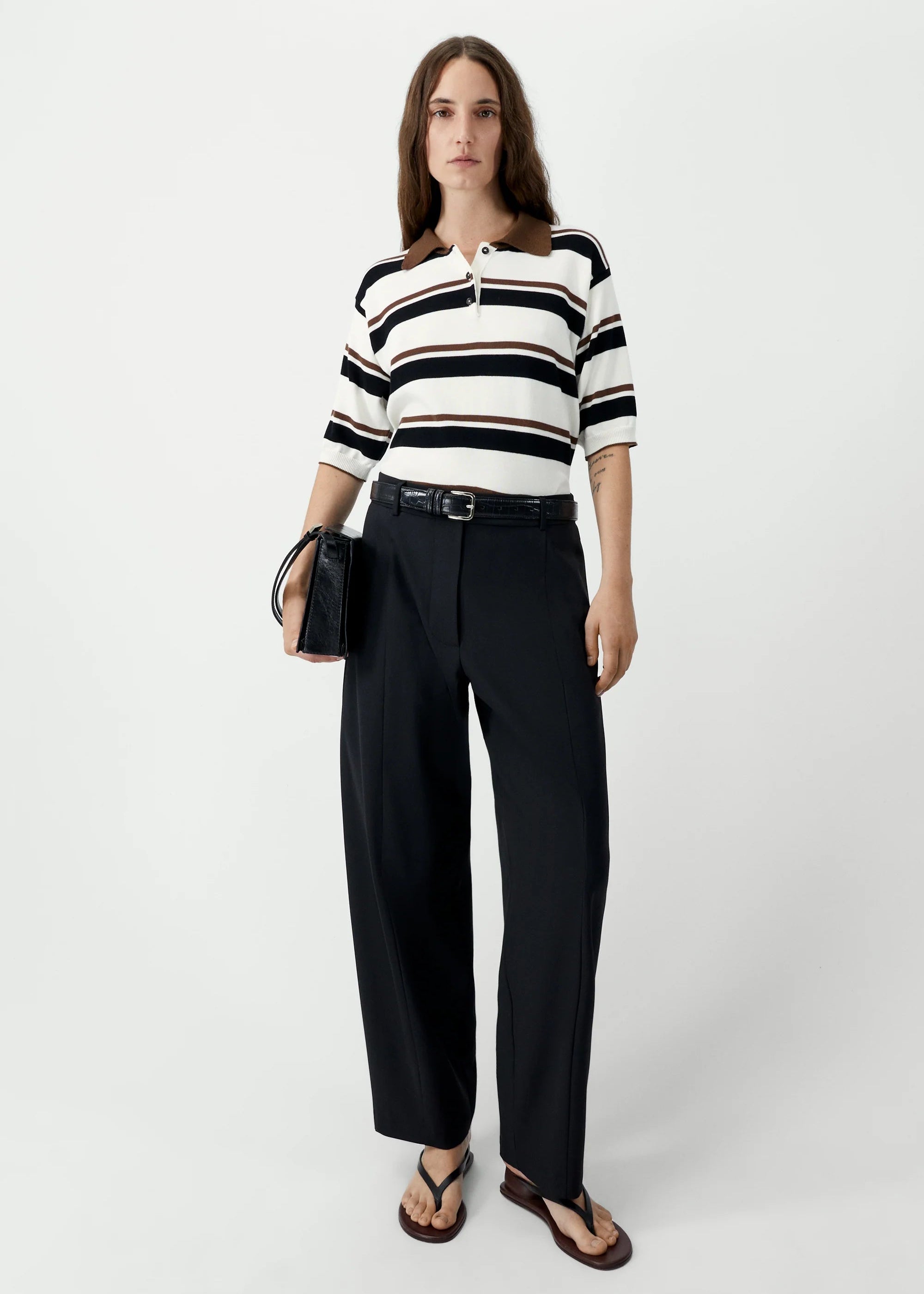 Woman wearing a black and white striped shirt with black pants on a white background
