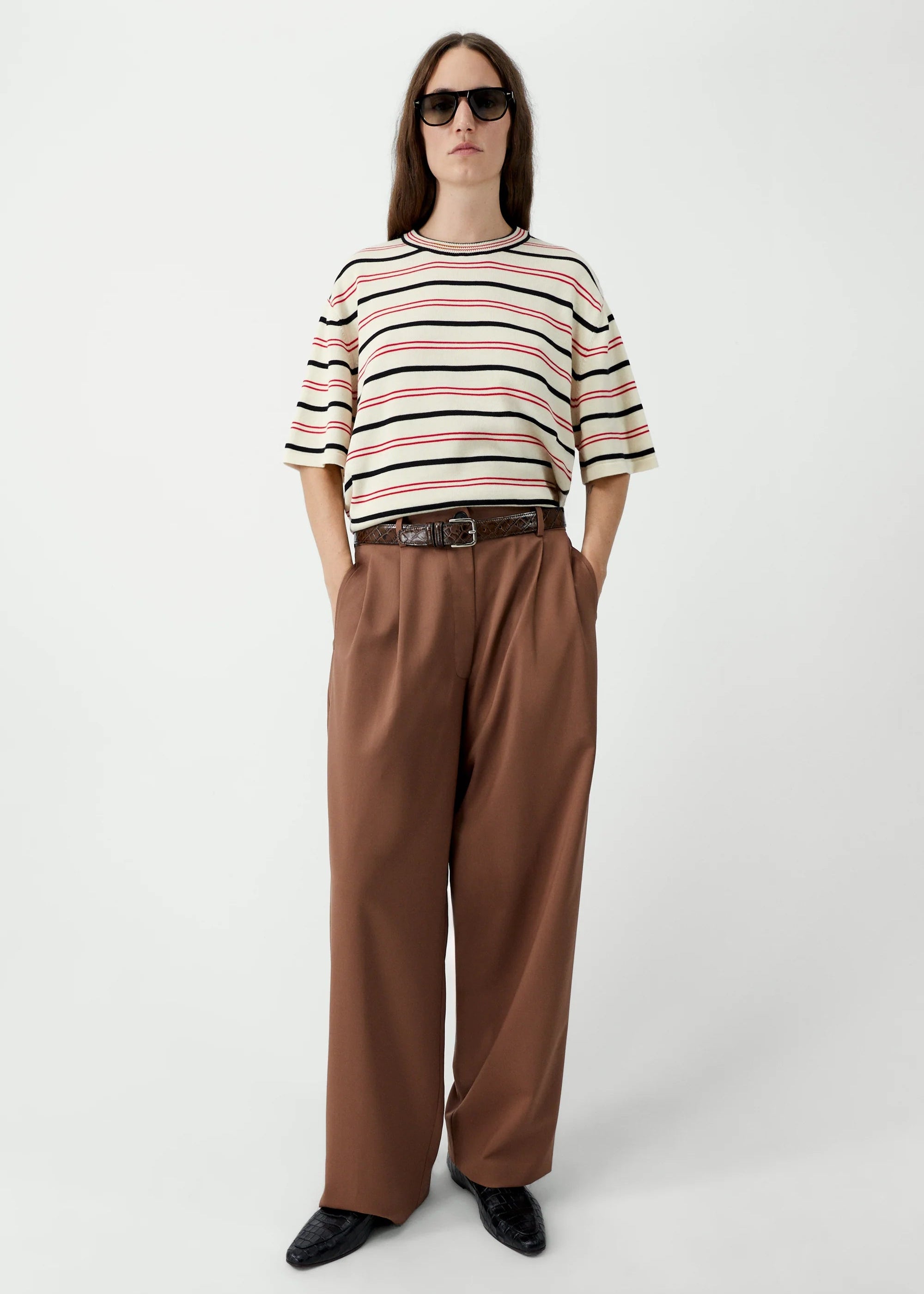 Person wearing a striped sweater and brown pants on a white background